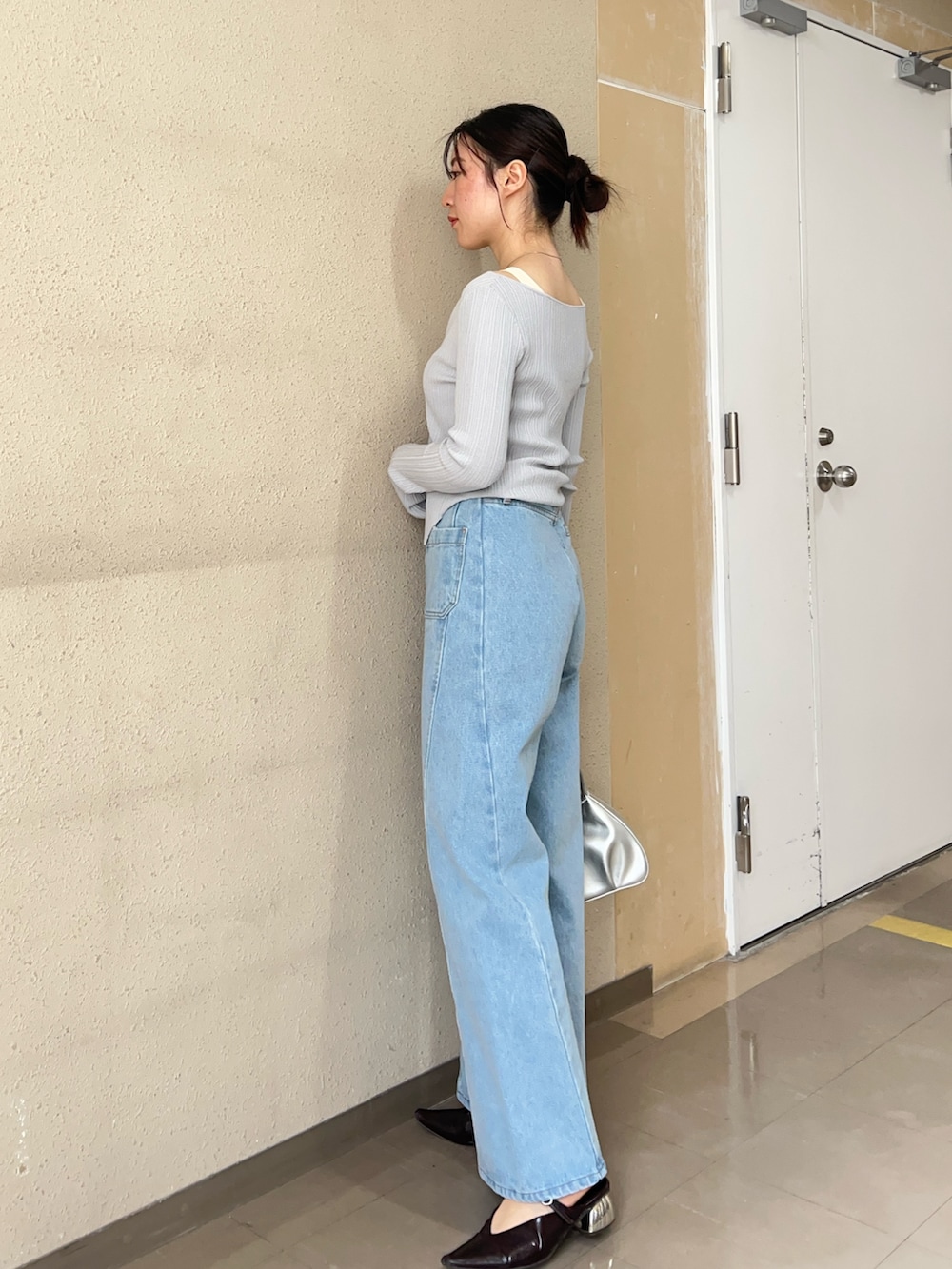 グレー系のニット/セーター、ブルー系のデニムパンツ、ブラック系のパンプスを着用したレディースの春コーディネートの2枚目の写真