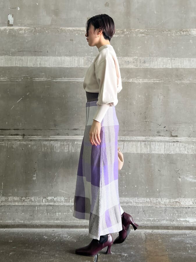 ホワイト系のニット/セーター、レッド系のブーツ、パープル系のスカートを着用したレディースの秋コーディネートの2枚目の写真