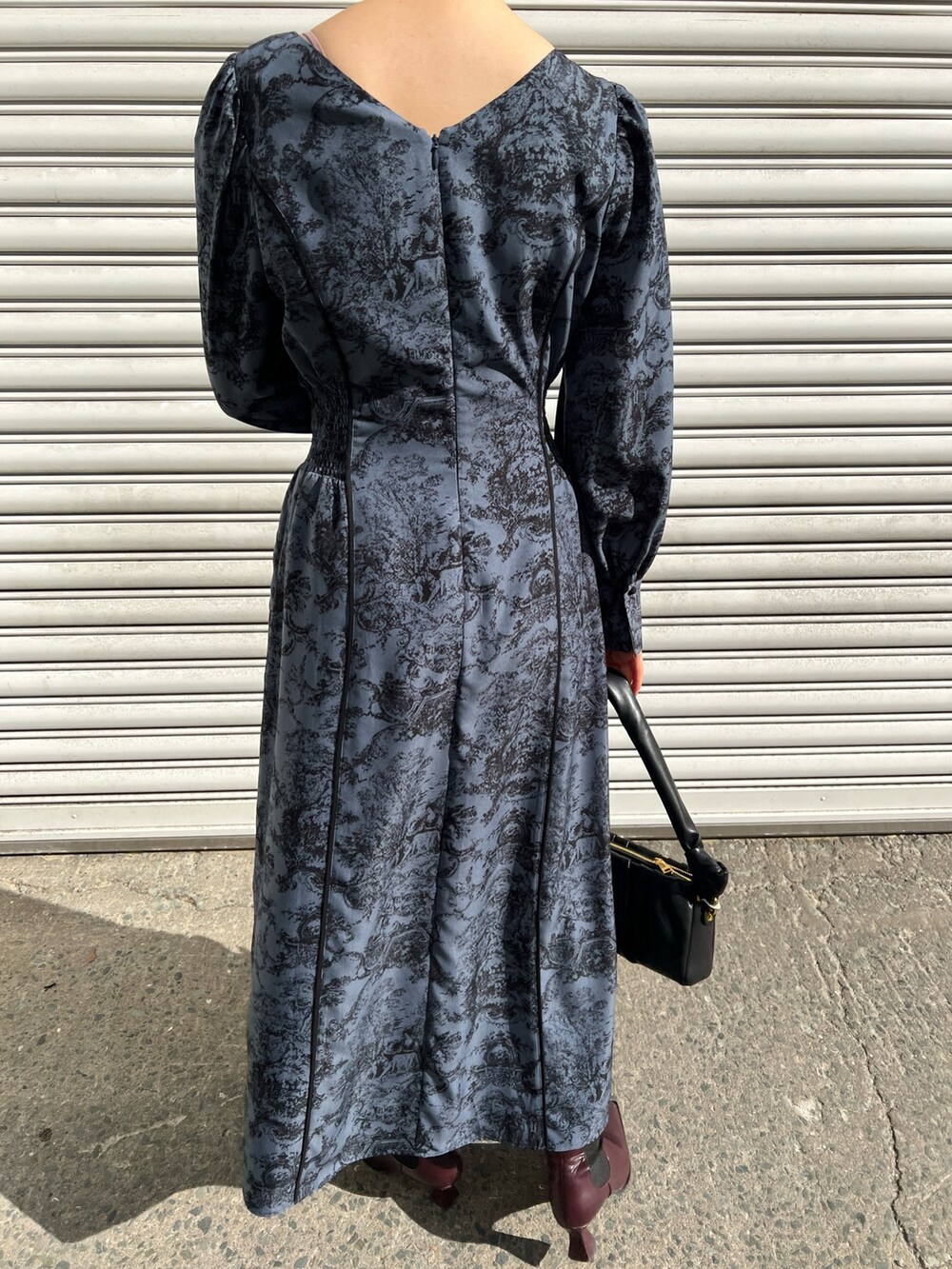 レッド系のブーツ、ブラック系のノーカラーコート、ブルー系のワンピースを着用したレディースの冬コーディネートの9枚目の写真