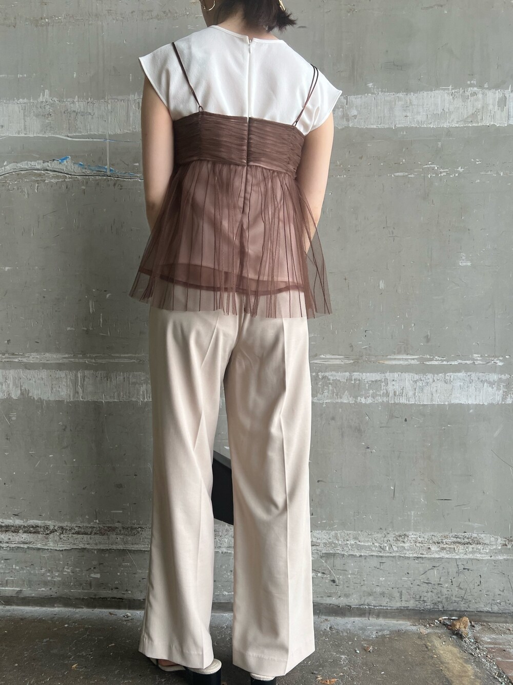 ブラック系のサンダル、ブラック系のショルダーバッグ、ホワイト系のスラックスを着用したレディースの夏コーディネートの9枚目の写真