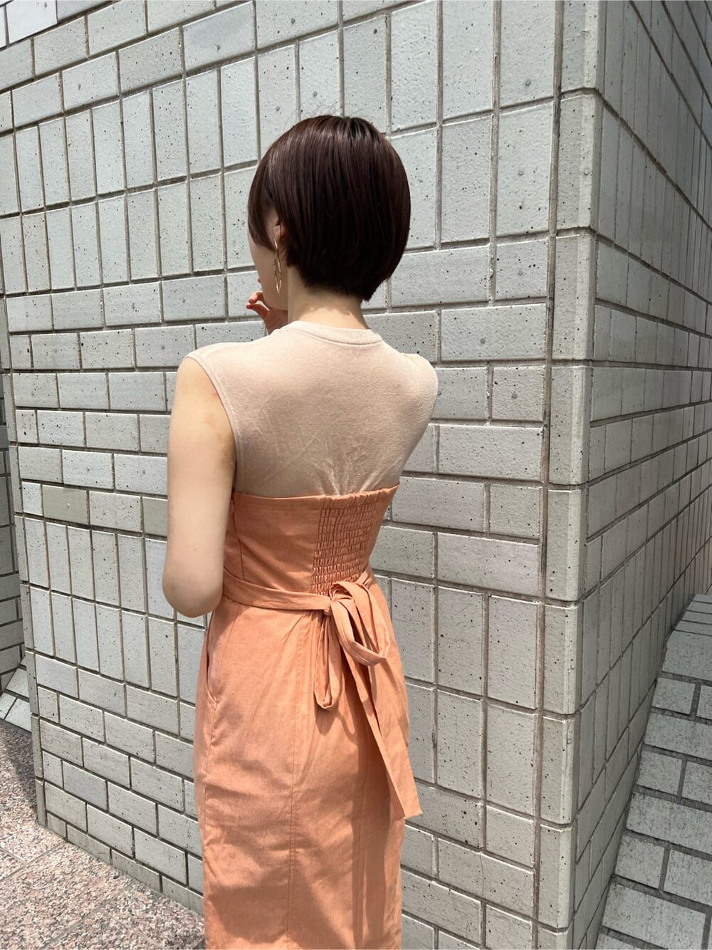 ホワイト系のブルゾン、オレンジ系のワンピース、ホワイト系のサンダルを着用したレディースの春コーディネートの8枚目の写真