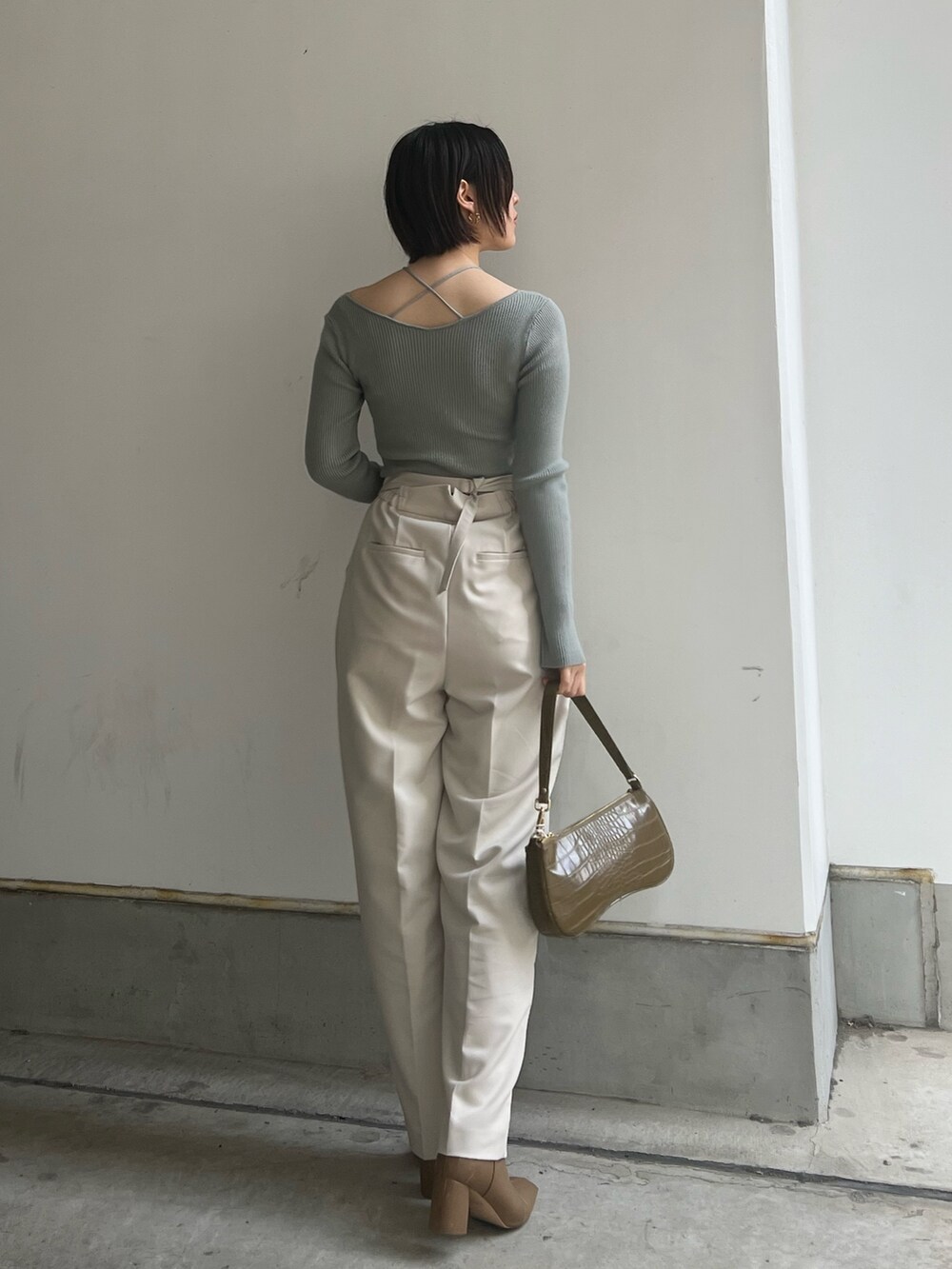 ベージュ系のブーツ、ホワイト系のスラックス、ホワイト系のニット/セーターを着用したレディースの冬コーディネートの2枚目の写真