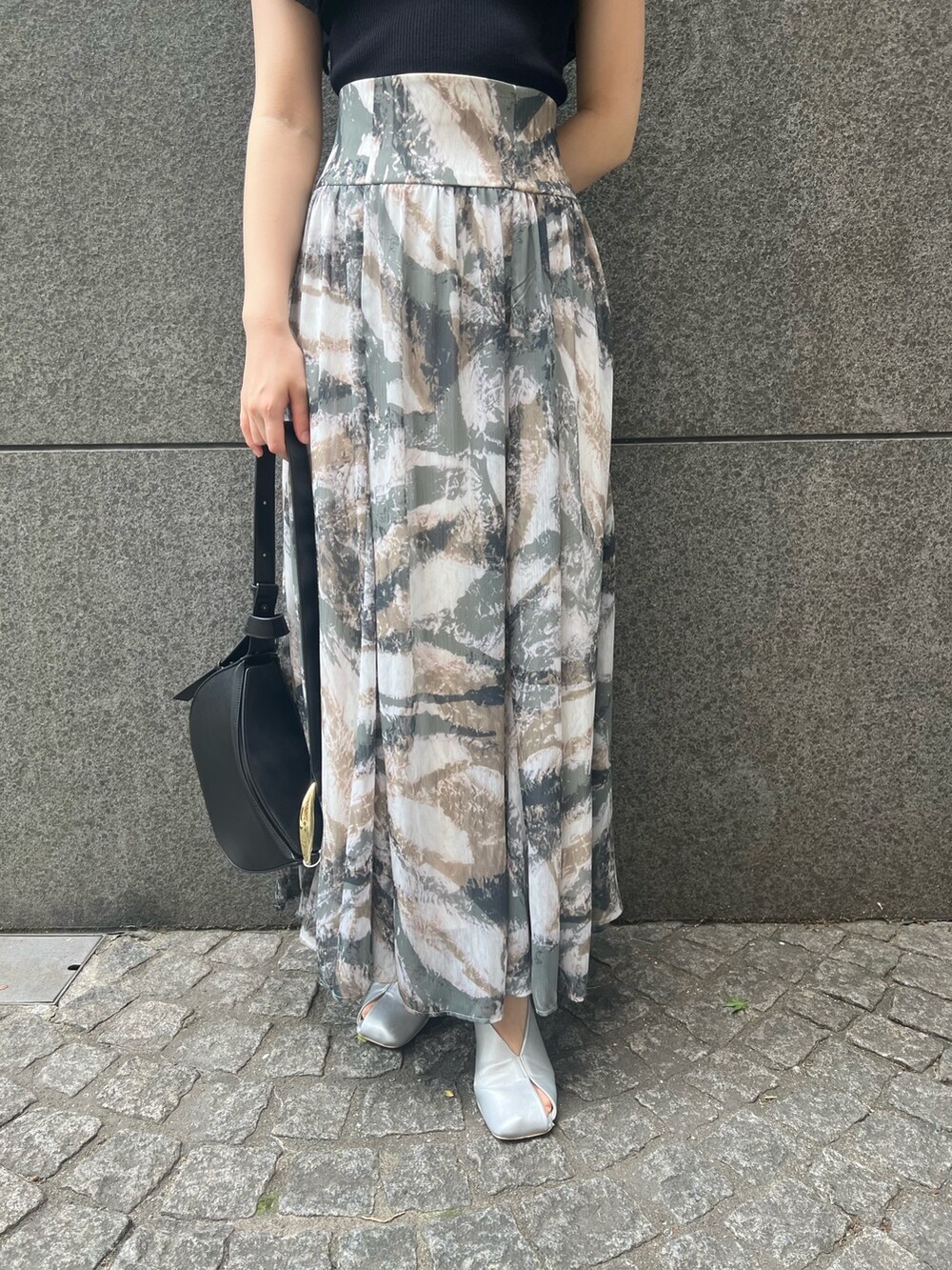 ブラック系のニット/セーター、グレー系のスカート、ブラック系のショルダーバッグを着用したレディースの春コーディネートの7枚目の写真