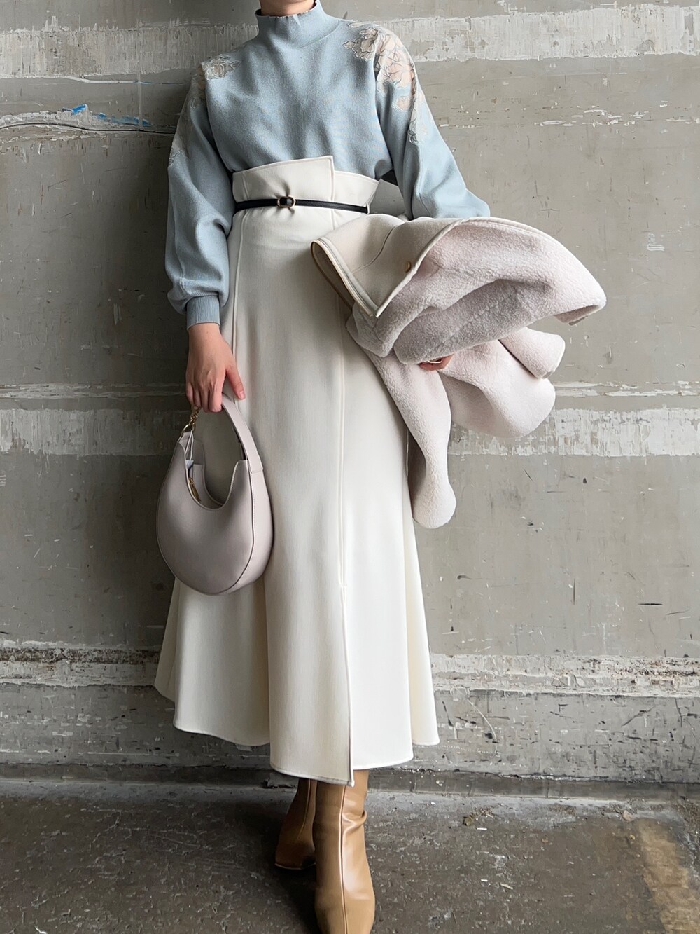 ベージュ系のブーツ、ホワイト系のハンドバッグ、ホワイト系のムートンコートを着用したレディースの秋コーディネートの6枚目の写真