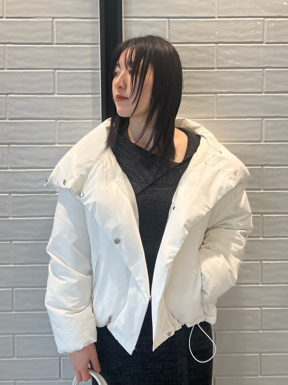 ホワイト系のダウンジャケット/コート、ブラック系のワンピース、ブラック系のブーツを着用したレディースの冬コーディネートの3枚目の写真