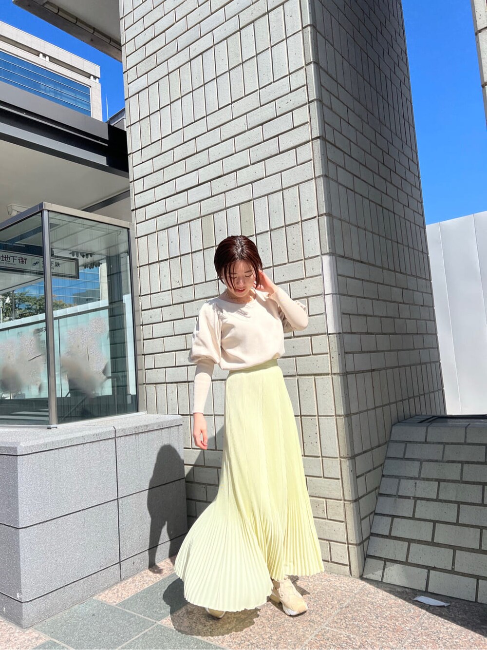 ブルー系のブルゾン、イエロー系のスカート、ベージュ系のニット/セーターを着用したレディースの春コーディネートの2枚目の写真