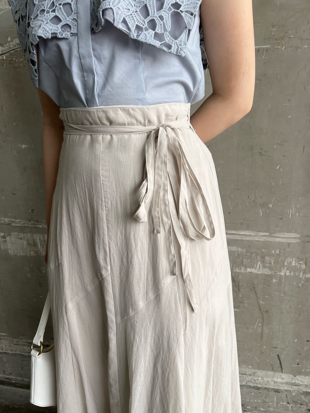 ベージュ系のサンダル、ホワイト系のハンドバッグ、グレー系のスカートを着用したレディースの夏コーディネートの8枚目の写真