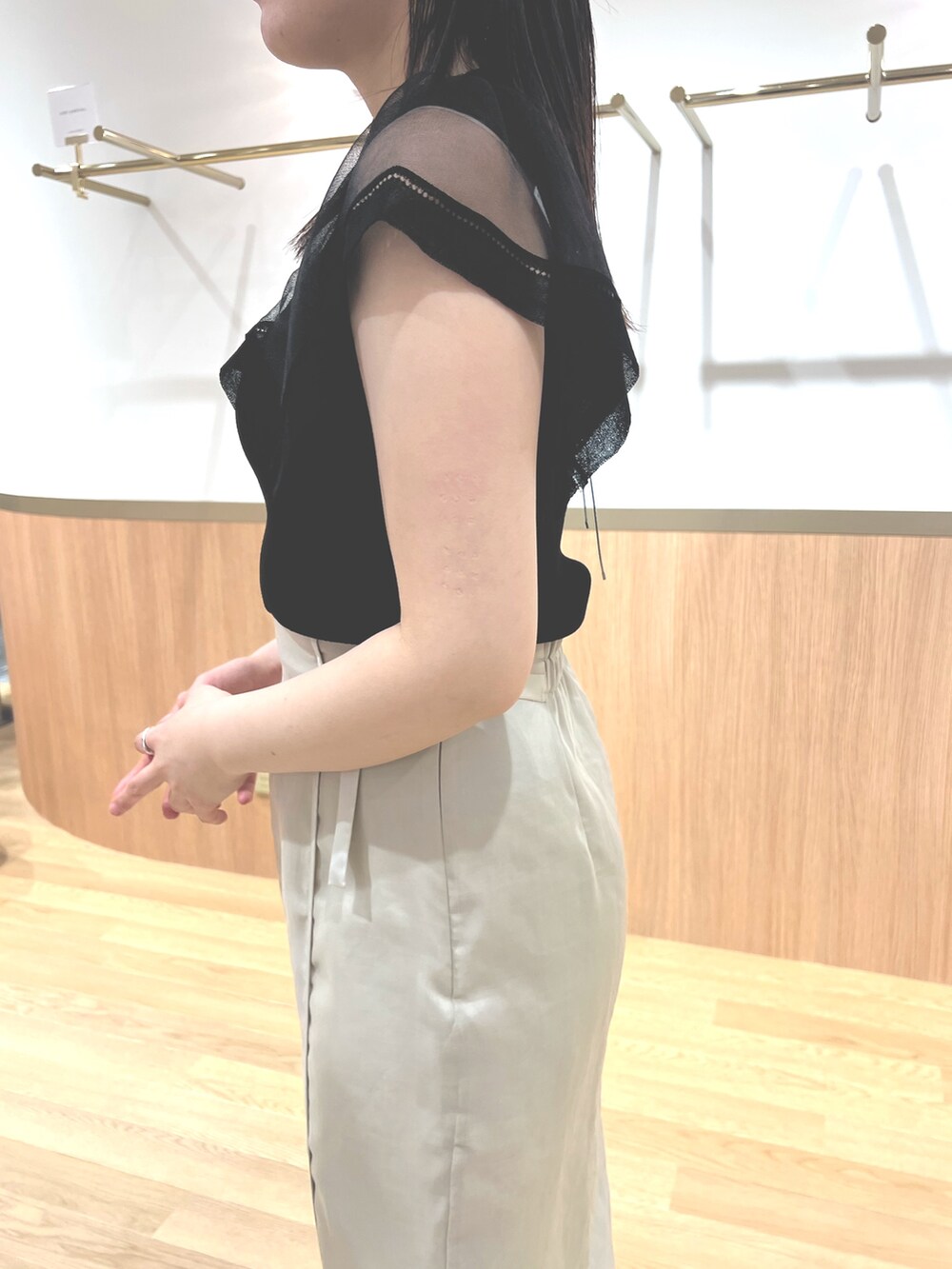 ブラック系のニット/セーター、ホワイト系のスカート、ホワイト系のサンダルを着用したレディースの春コーディネートの5枚目の写真