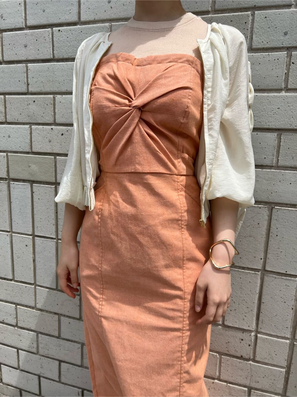 ホワイト系のブルゾン、オレンジ系のワンピース、ホワイト系のサンダルを着用したレディースの春コーディネートの9枚目の写真