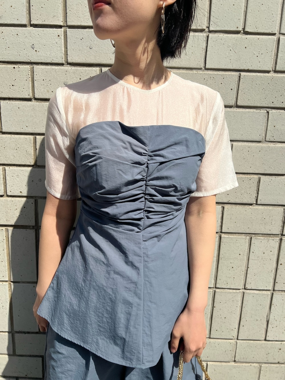 ゴールド系のパンプス、ゴールド系のハンドバッグ、ブルー系のパンツドレスを着用したレディースの春コーディネートの5枚目の写真