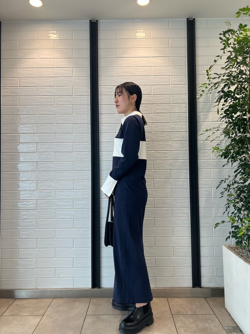 ブラック系のハンドバッグ、ブラック系のブーツ、ブルー系のワンピースを着用したレディースの秋コーディネートの2枚目の写真