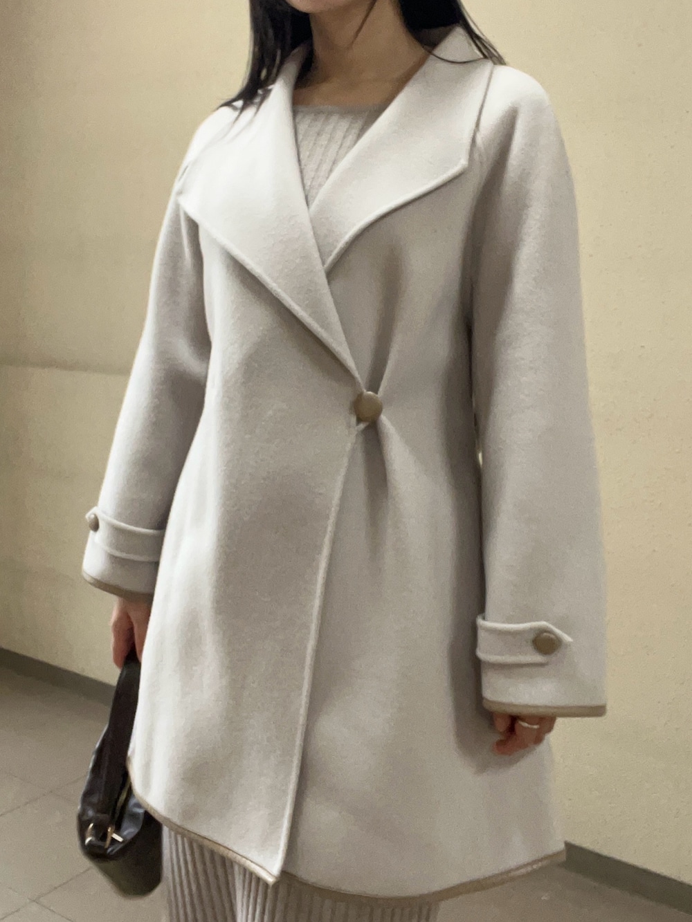 ブラック系のブーツ、ベージュ系のワンピース、ホワイト系のその他アウターを着用したレディースの秋コーディネートの3枚目の写真