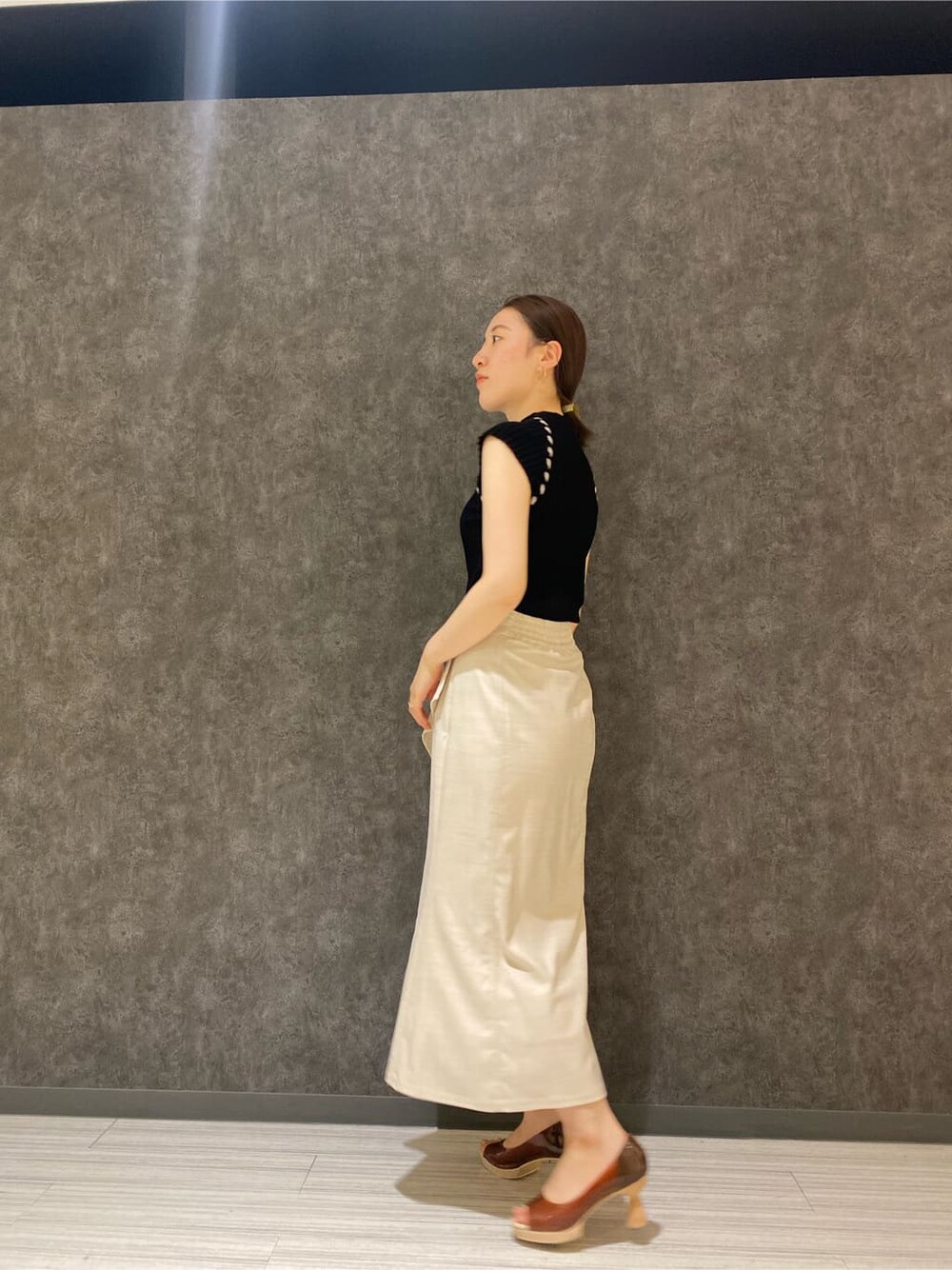 ブラウン系のパンプス、ホワイト系のスカート、ブラック系のニット/セーターを着用したレディースの夏コーディネートの4枚目の写真