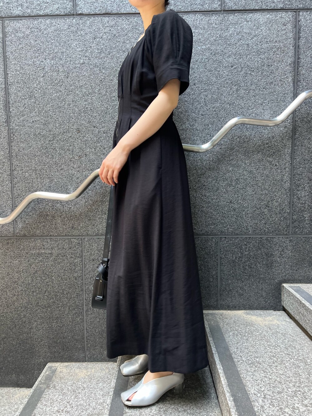 ブラック系のワンピース、ブラック系のショルダーバッグ、シルバー系のパンプスを着用したレディースの夏コーディネートの7枚目の写真