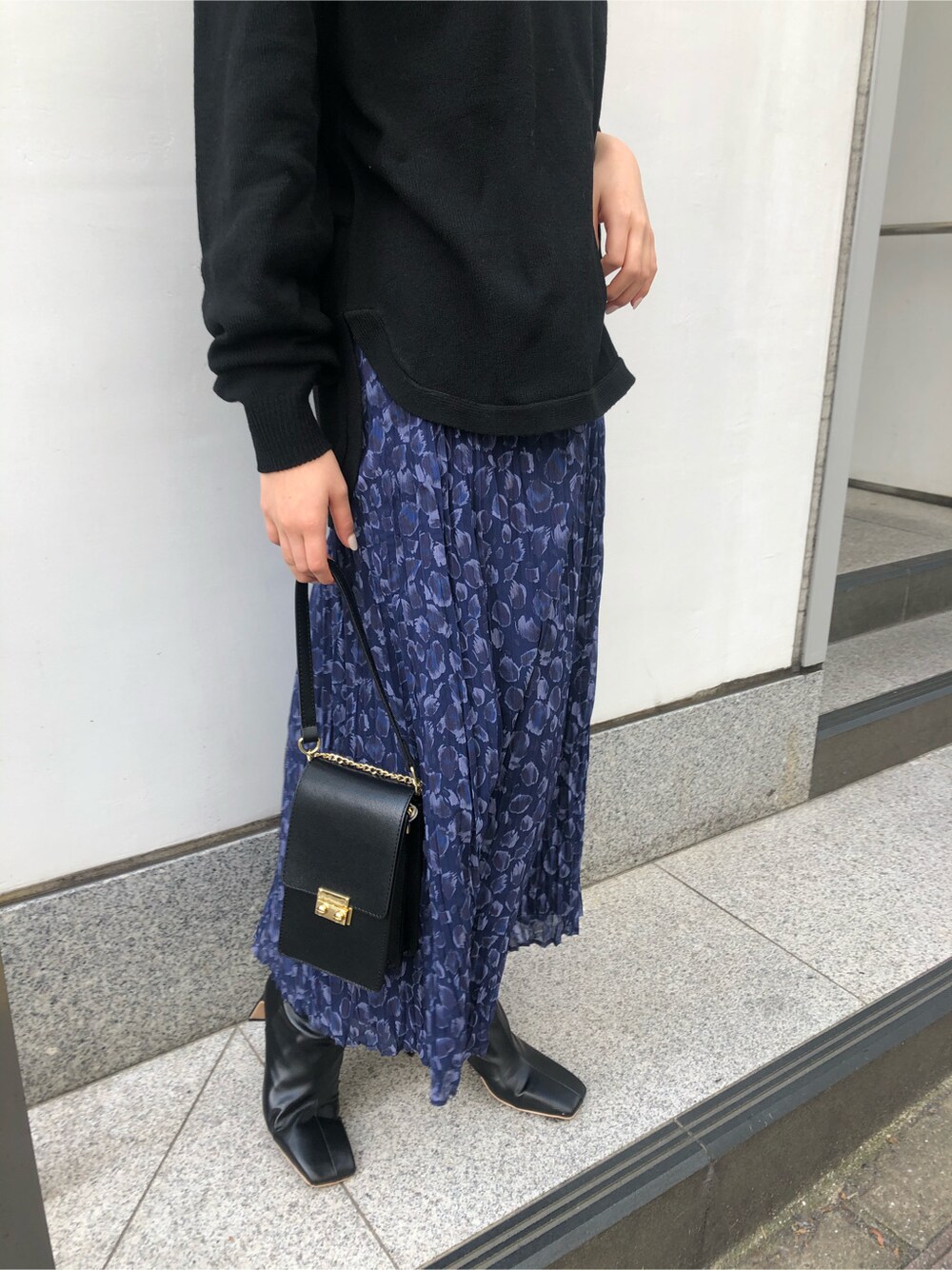 ブラック系のその他アウター、ブラック系のニット/セーター、ブルー系のスカートを着用したレディースの秋コーディネートの3枚目の写真