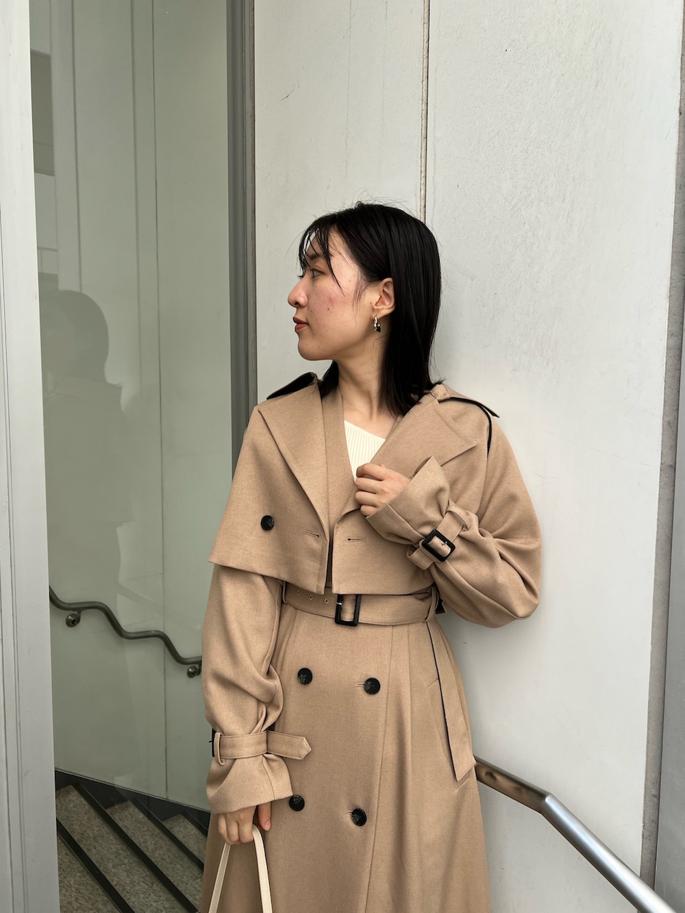 ベージュ系のトレンチコート、ホワイト系のショルダーバッグ、ホワイト系のニット/セーターを着用したレディースの秋コーディネートの3枚目の写真