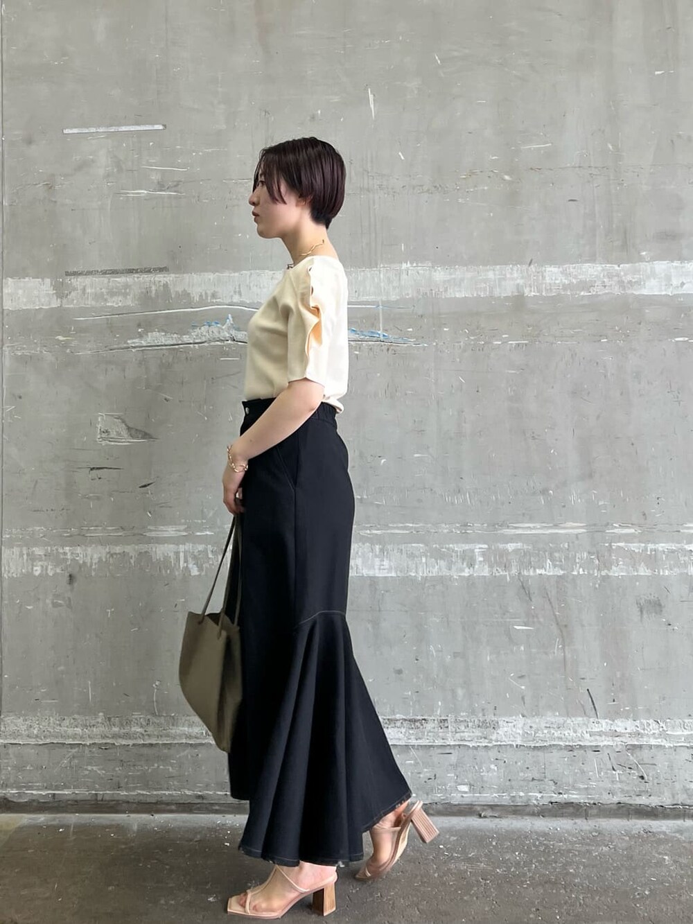 ベージュ系のハンドバッグ、ブラック系のスカート、ホワイト系のニット/セーターを着用したレディースの夏コーディネートの3枚目の写真