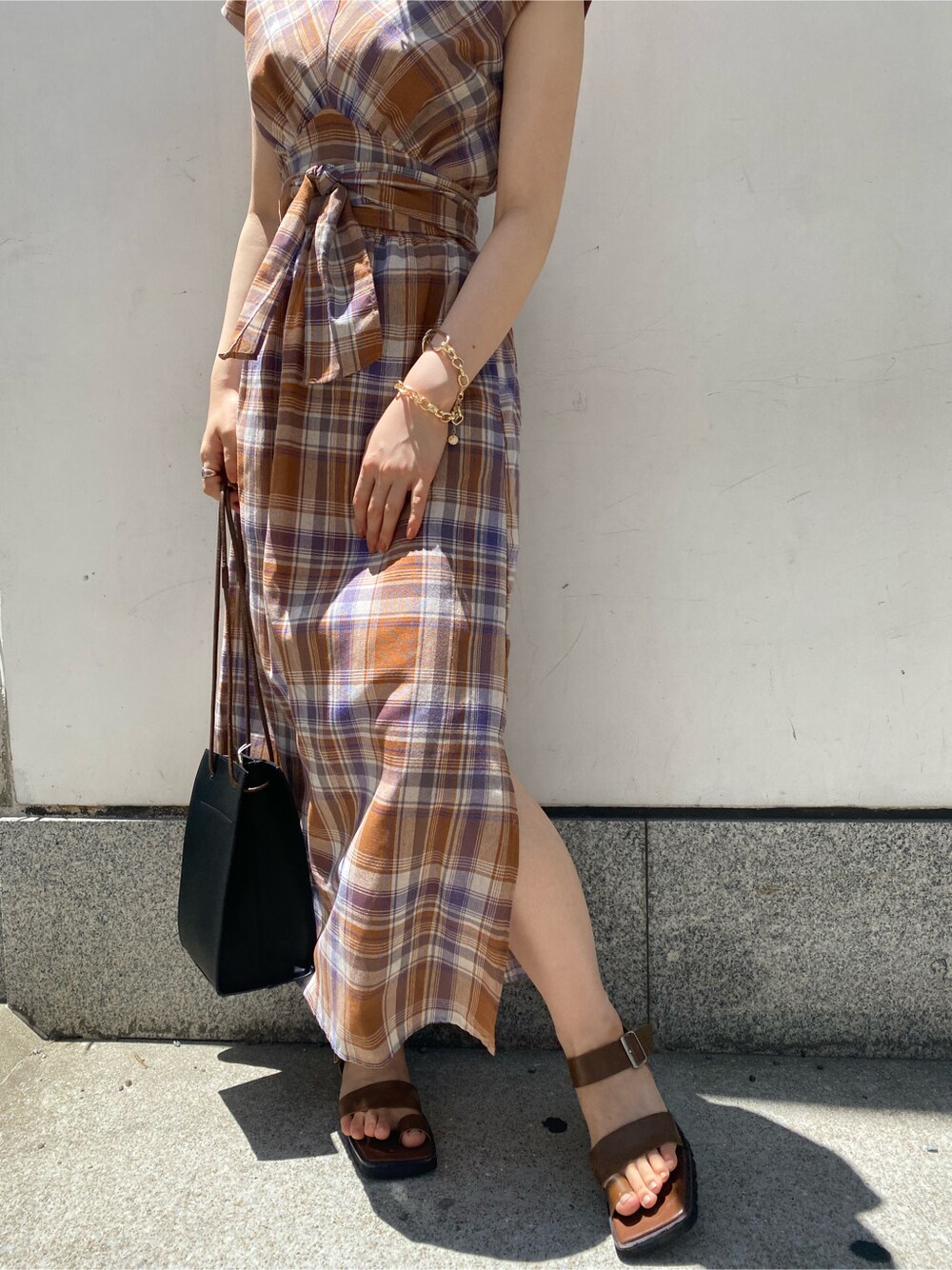 ブラック系のハンドバッグ、ブラウン系のサンダル、ブラウン系のワンピースを着用したレディースの夏コーディネートの6枚目の写真