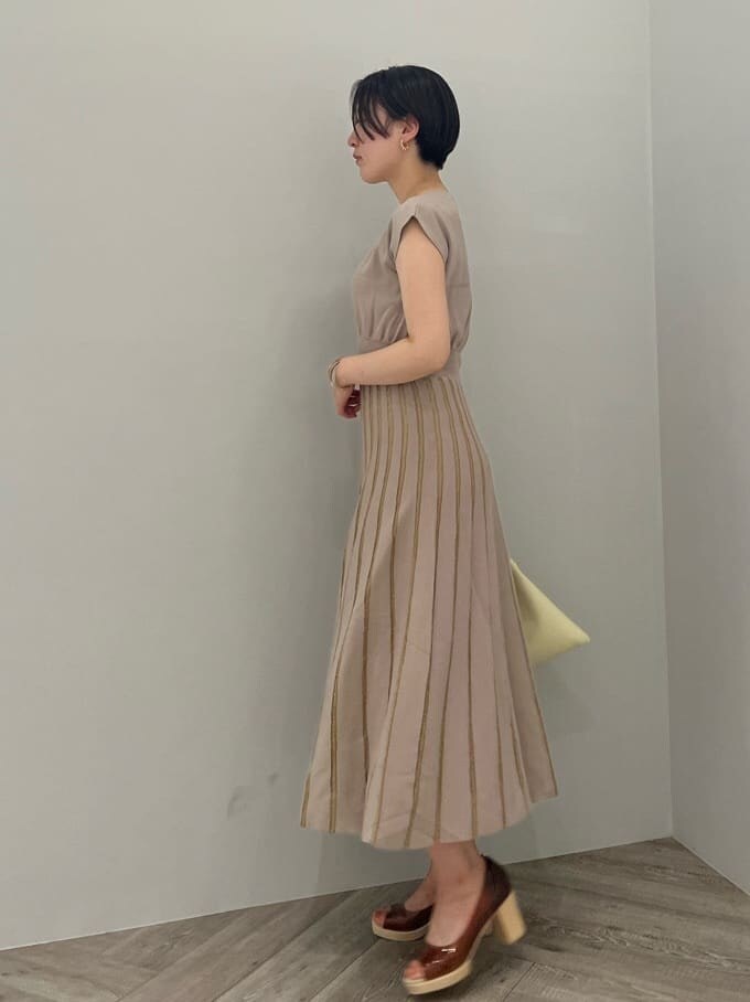 ホワイト系のハンドバッグ、ブラウン系のパンプス、ベージュ系のワンピースを着用したレディースの夏コーディネートの2枚目の写真