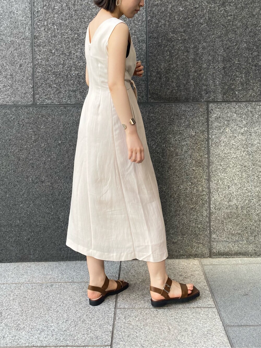 ブルー系のデニムパンツ、ブラウン系のサンダル、ベージュ系のワンピースを着用したレディースの春コーディネートの7枚目の写真