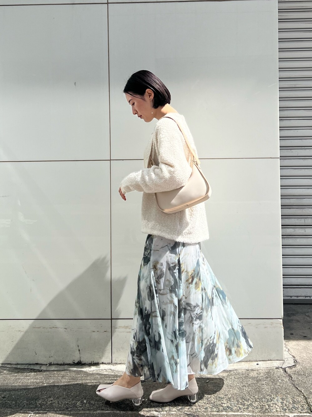 ホワイト系のパンプス、ベージュ系のハンドバッグ、ホワイト系のニット/セーターを着用したレディースの春コーディネートの2枚目の写真