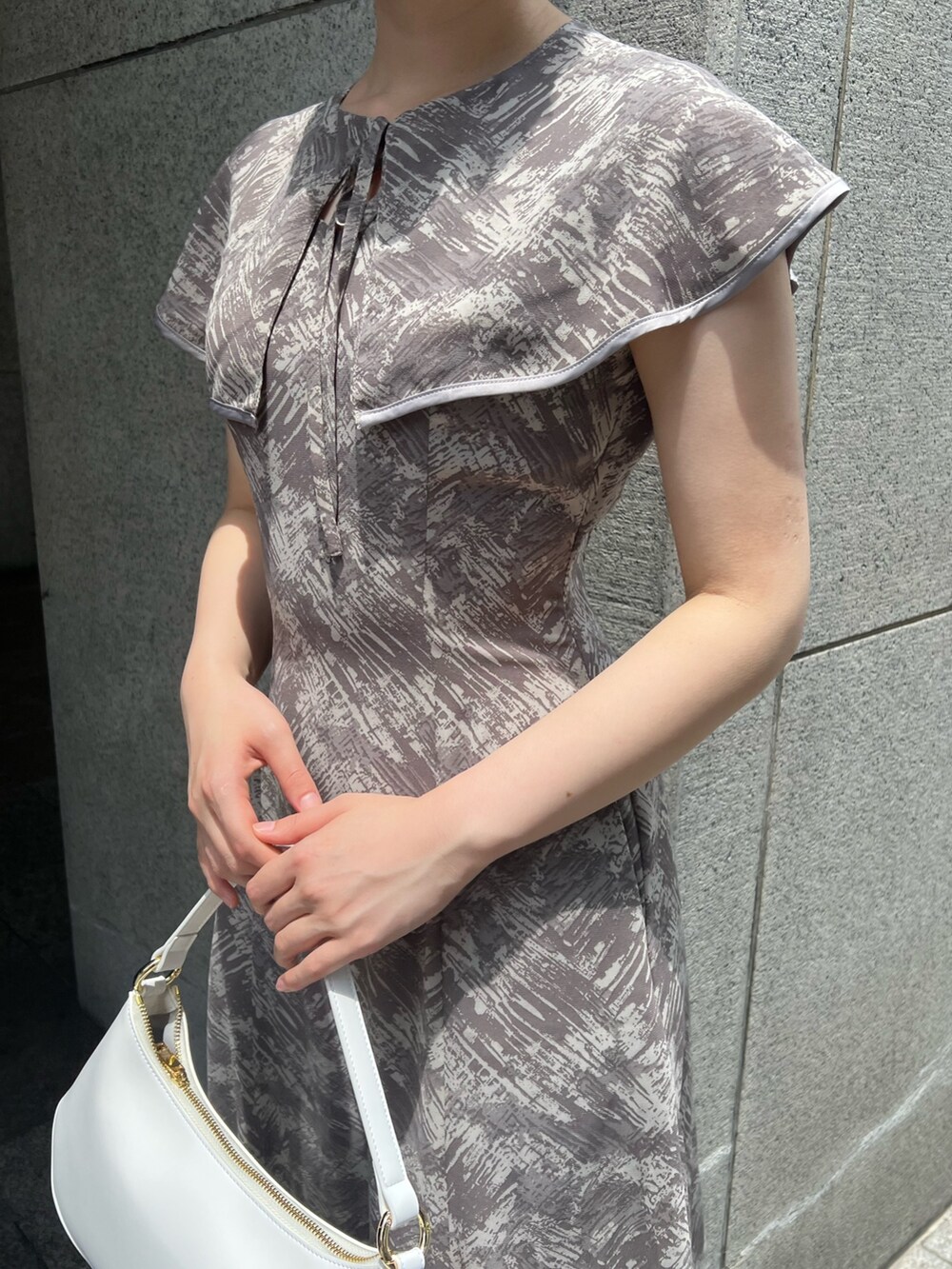 ホワイト系のハンドバッグ、ベージュ系のサンダル、グレー系のワンピースを着用したレディースの夏コーディネートの5枚目の写真