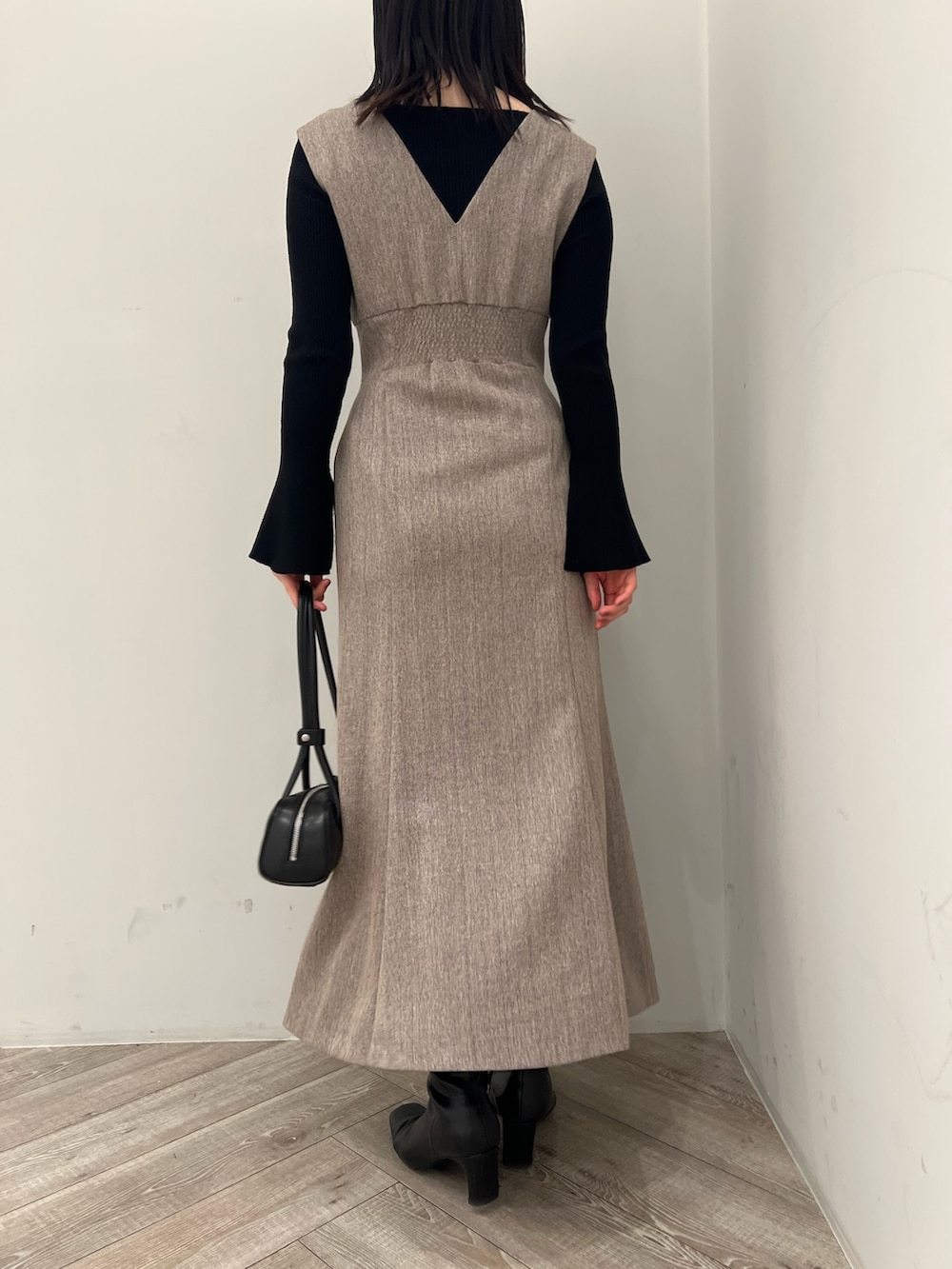 ホワイト系のブルゾン、ベージュ系のジャンパースカート、ブラック系のニット/セーターを着用したレディースの冬コーディネートの10枚目の写真