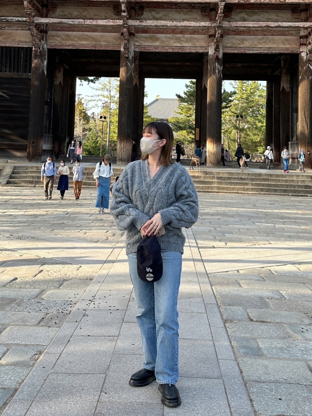 ブルー系のデニムパンツ、グレー系のニット/セーター、ブルー系のキャップを着用したレディースの春コーディネートの2枚目の写真