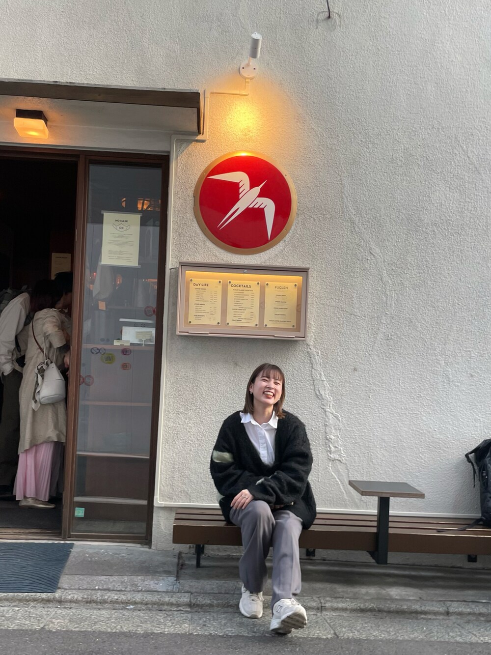 ブルー系のニット/セーター、ホワイト系のシャツ/ブラウス、グレー系のスラックスを着用したレディースの春コーディネートの2枚目の写真