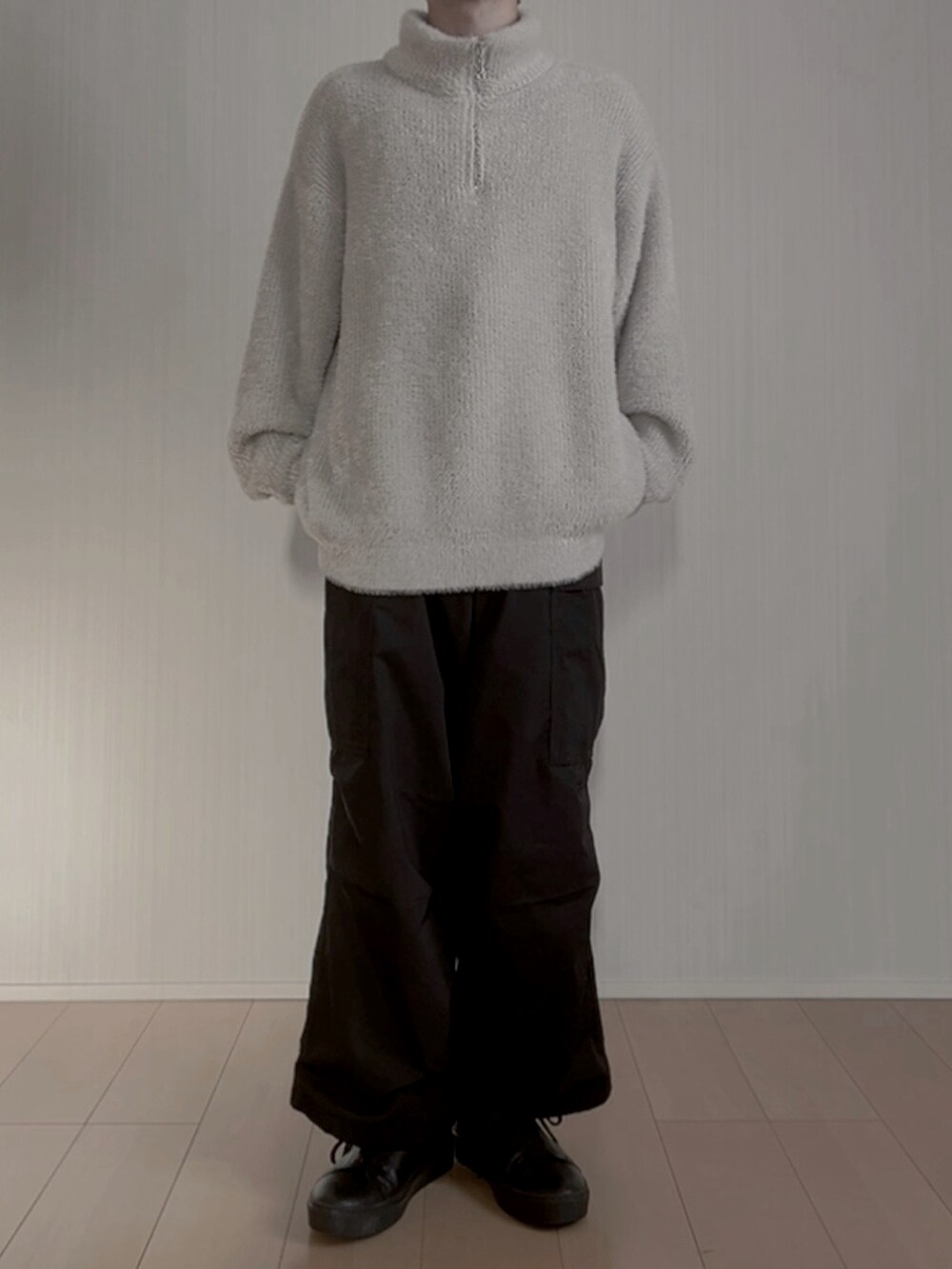 グレー系のニット/セーター、ブラック系のカーゴパンツ、ブラック系のスニーカーを着用したメンズの春コーディネートの3枚目の写真