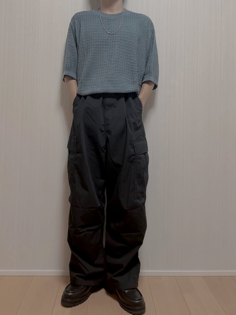 ブラック系のカーゴパンツ、ブラック系のモカシン/デッキシューズ、ブルー系のニット/セーターを着用したメンズの夏コーディネートの3枚目の写真