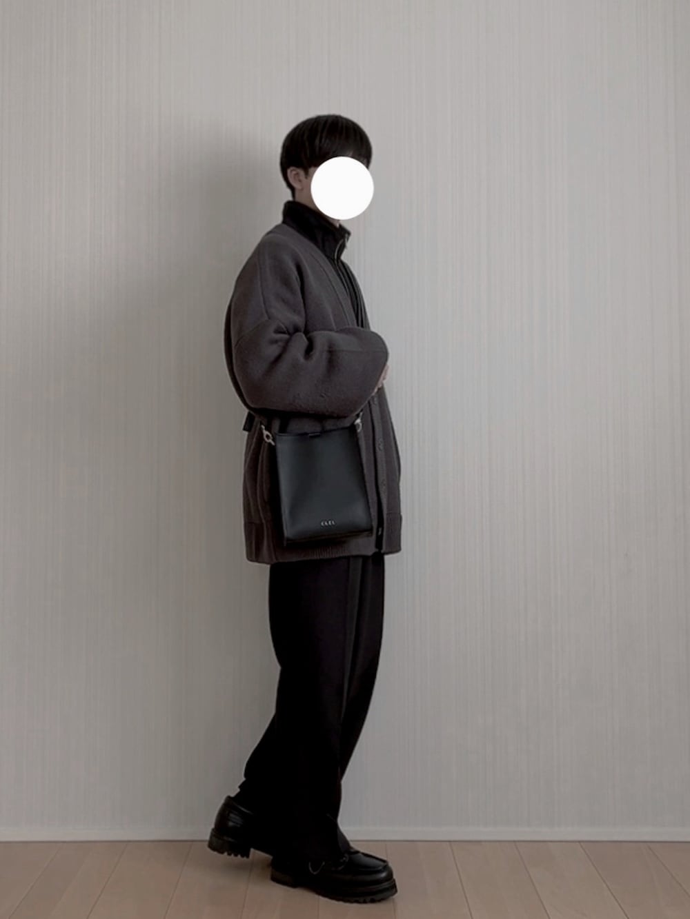 ブラック系のスラックス、ブラック系のモカシン/デッキシューズ、ブラック系のショルダーバッグを着用したメンズの冬コーディネートの3枚目の写真