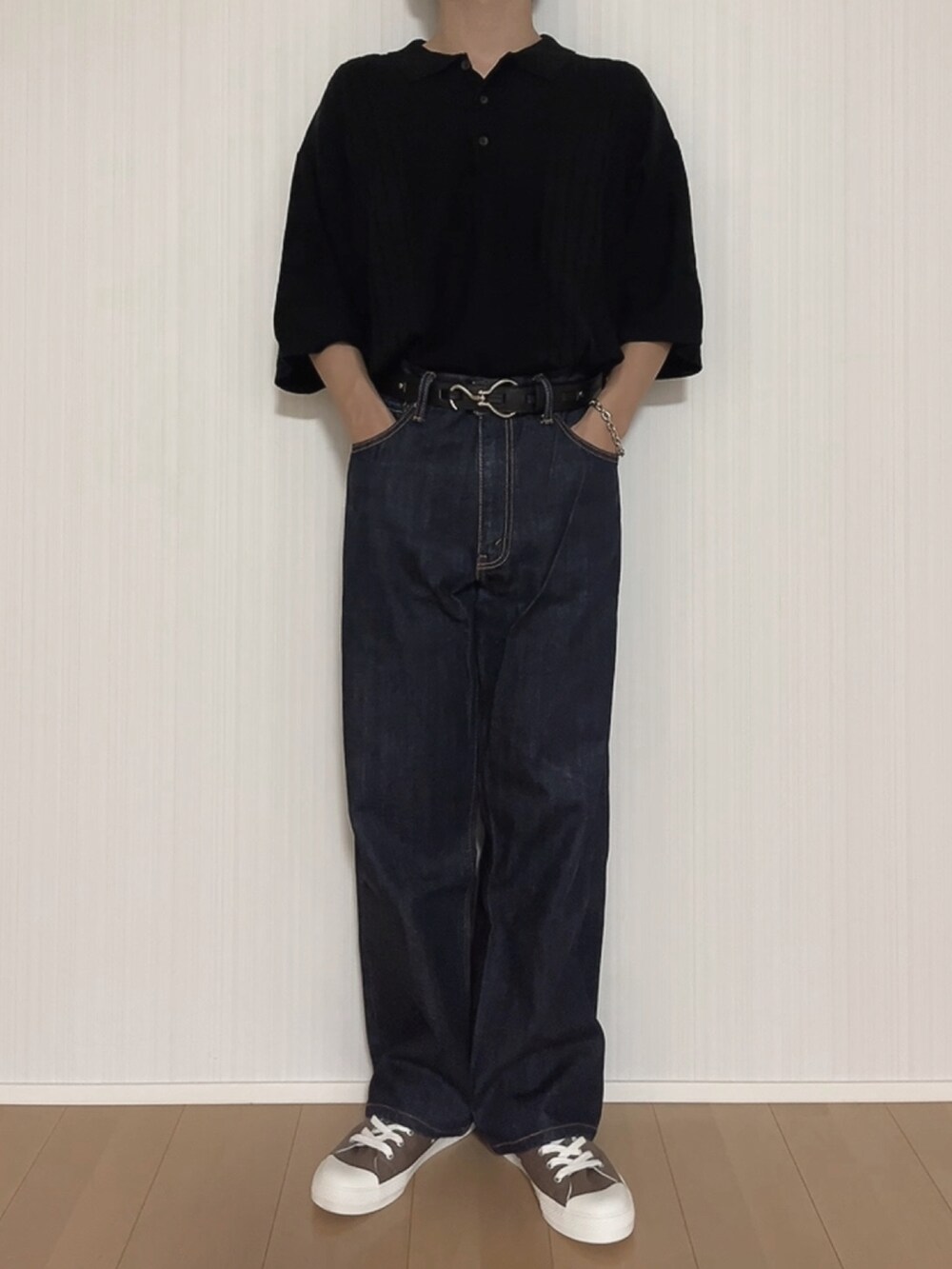 ブラック系のポロシャツ、ブルー系のデニムパンツ、ブラウン系のスニーカーを着用したメンズの秋コーディネートの3枚目の写真