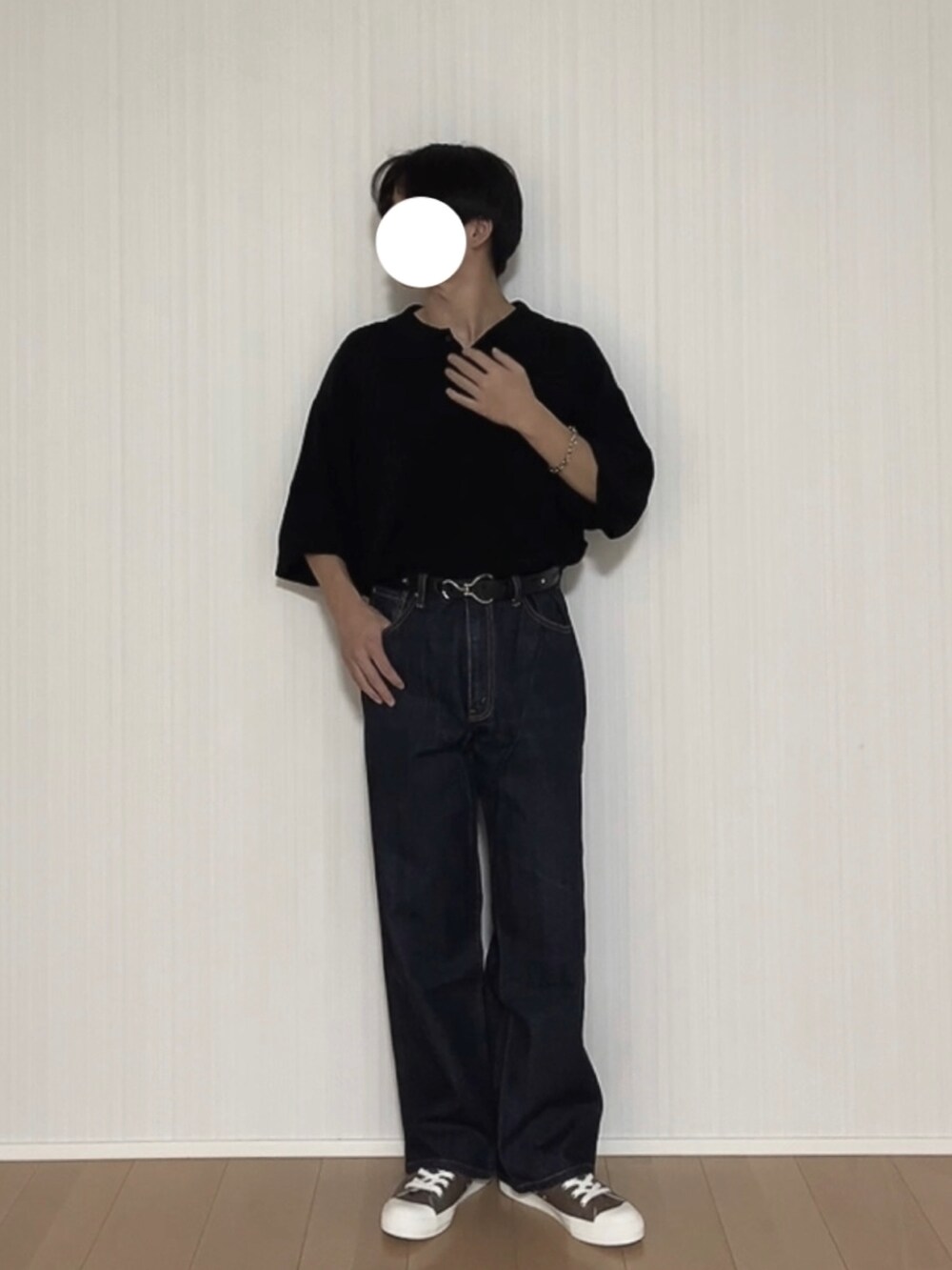 ブラック系のポロシャツ、ブルー系のデニムパンツ、ブラウン系のスニーカーを着用したメンズの秋コーディネートの2枚目の写真