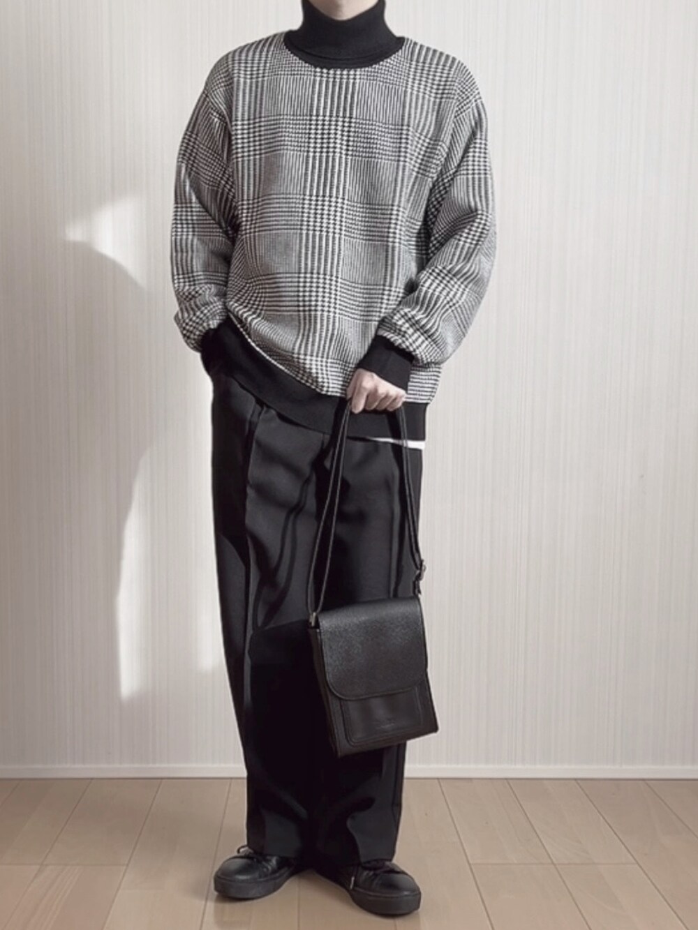 ブラック系のスラックス、ブラック系のスニーカー、ブラック系のニット/セーターを着用したメンズの冬コーディネートの5枚目の写真