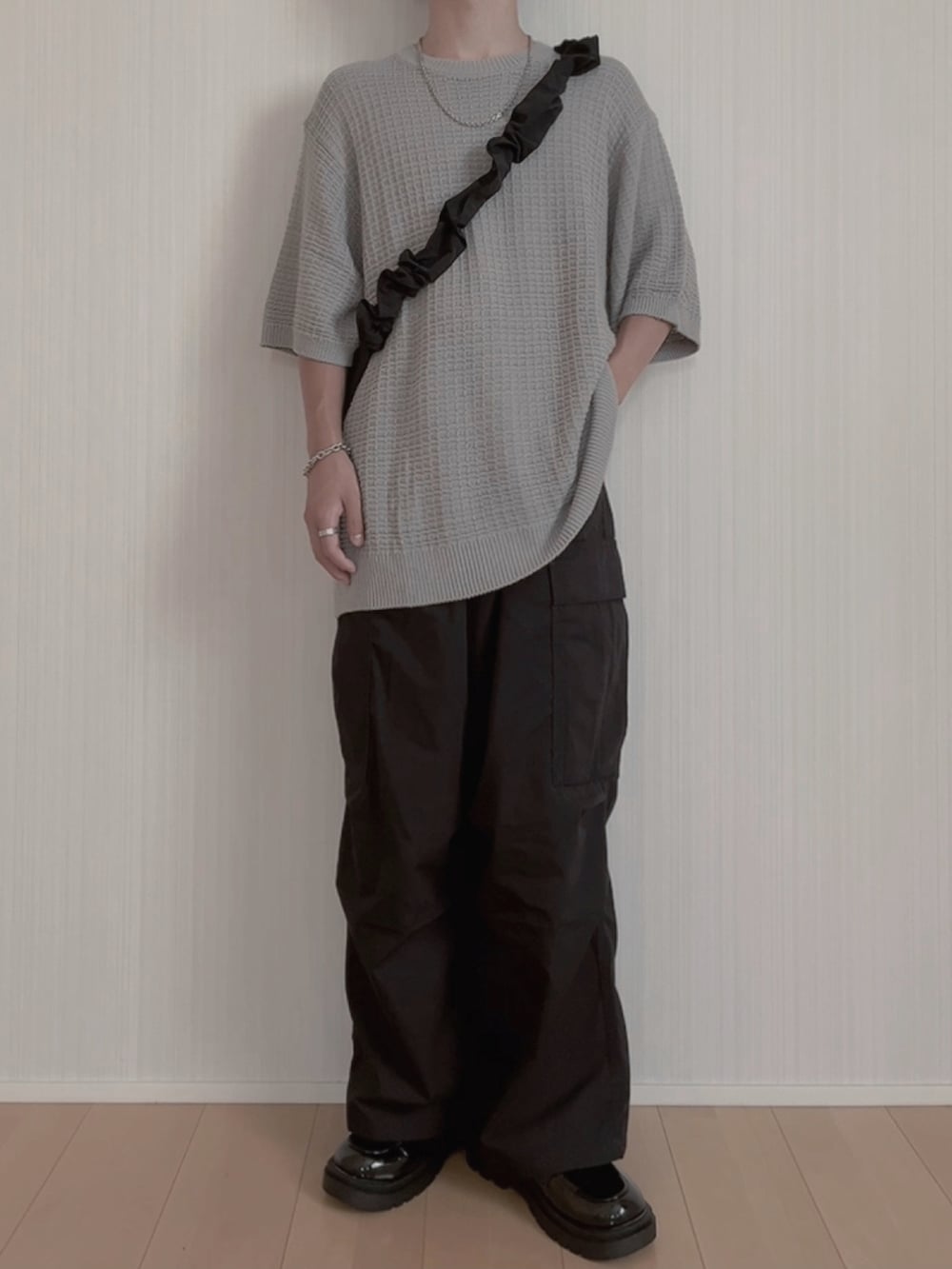 グレー系のニット/セーター、ブラック系のカーゴパンツ、ブラック系のローファーを着用したメンズの夏コーディネートの3枚目の写真