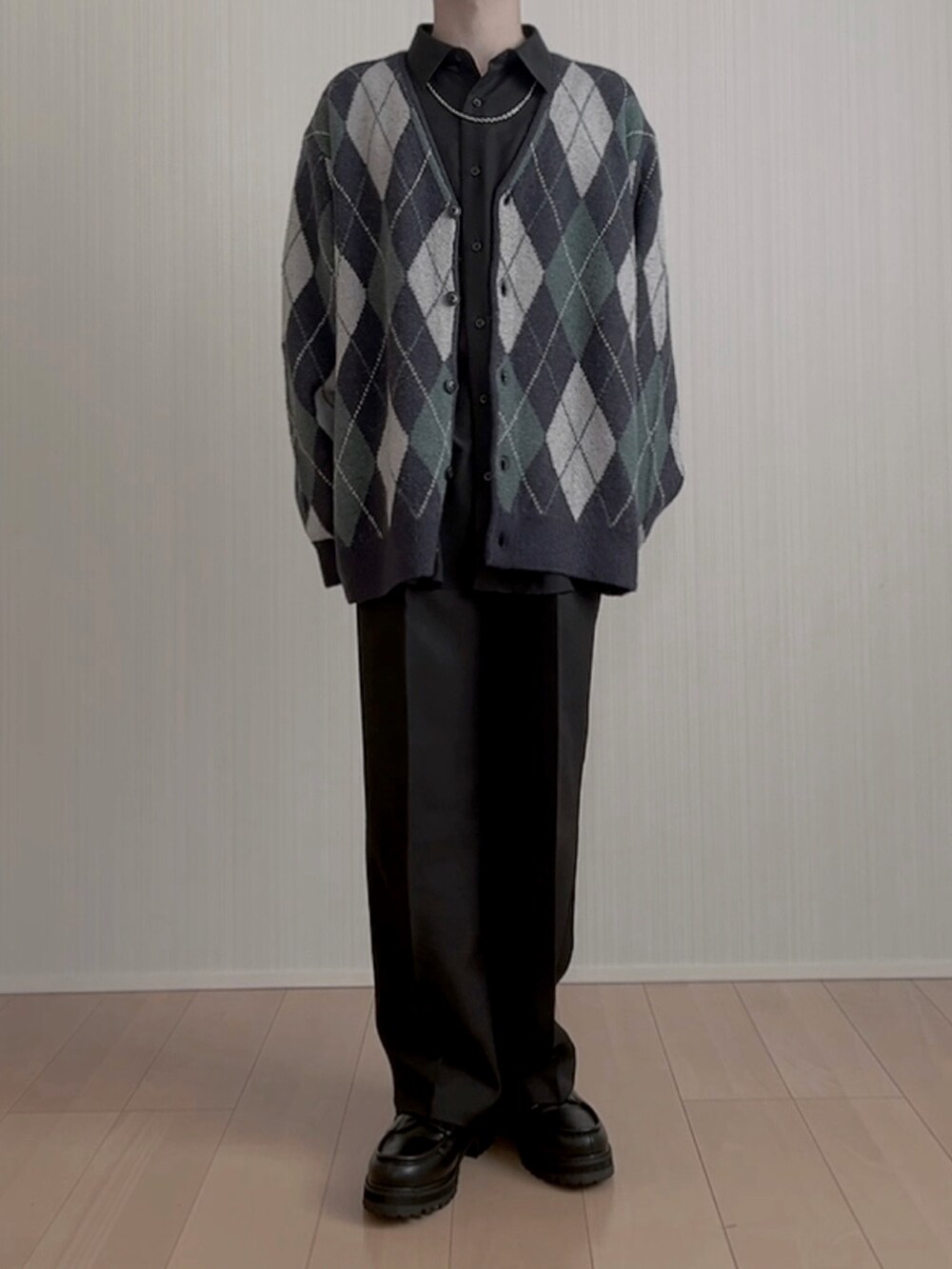 ブラック系のモカシン/デッキシューズ、ブラック系のスラックス、ブルー系のカーディガン/ボレロを着用したメンズの春コーディネートの5枚目の写真