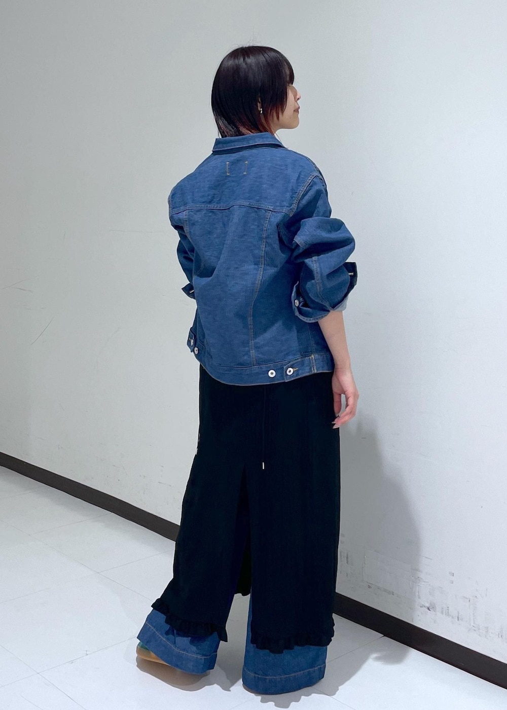 グリーン系のスニーカー、ブラック系のワンピース、ブルー系のブルゾンを着用したレディースの春コーディネートの3枚目の写真