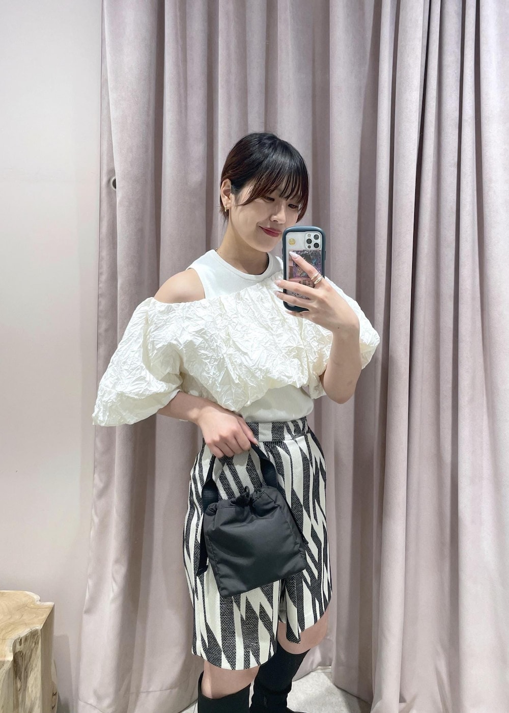 ブラック系のブーツ、ブラック系のハンドバッグ、ホワイト系のその他トップスを着用したレディースの春コーディネートの4枚目の写真