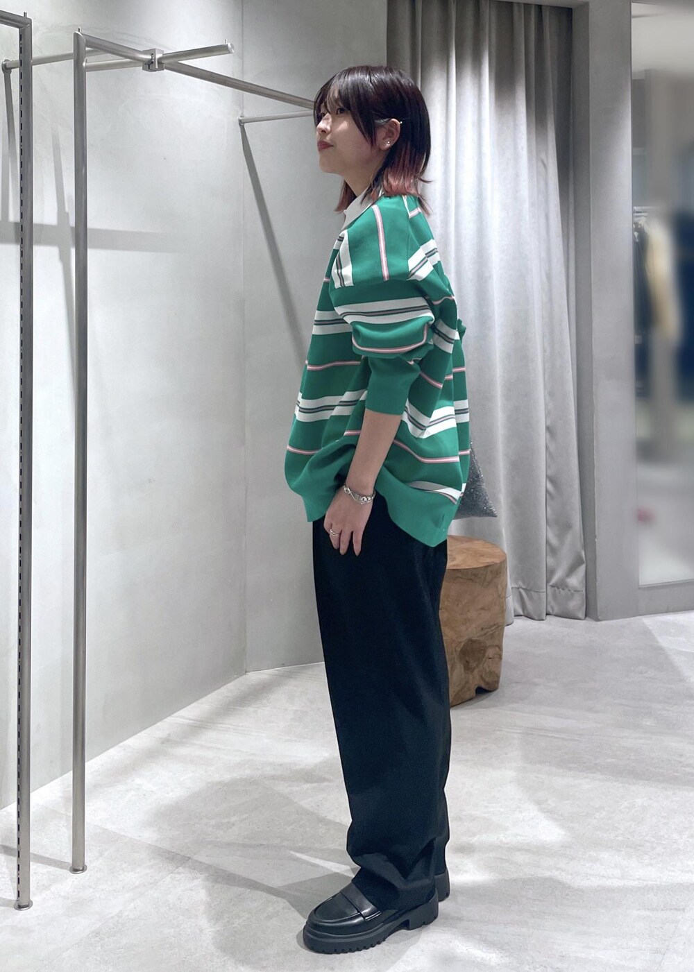 グリーン系のニット/セーター、ブラック系のスラックス、シルバー系のトートバッグを着用したレディースの冬コーディネートの3枚目の写真