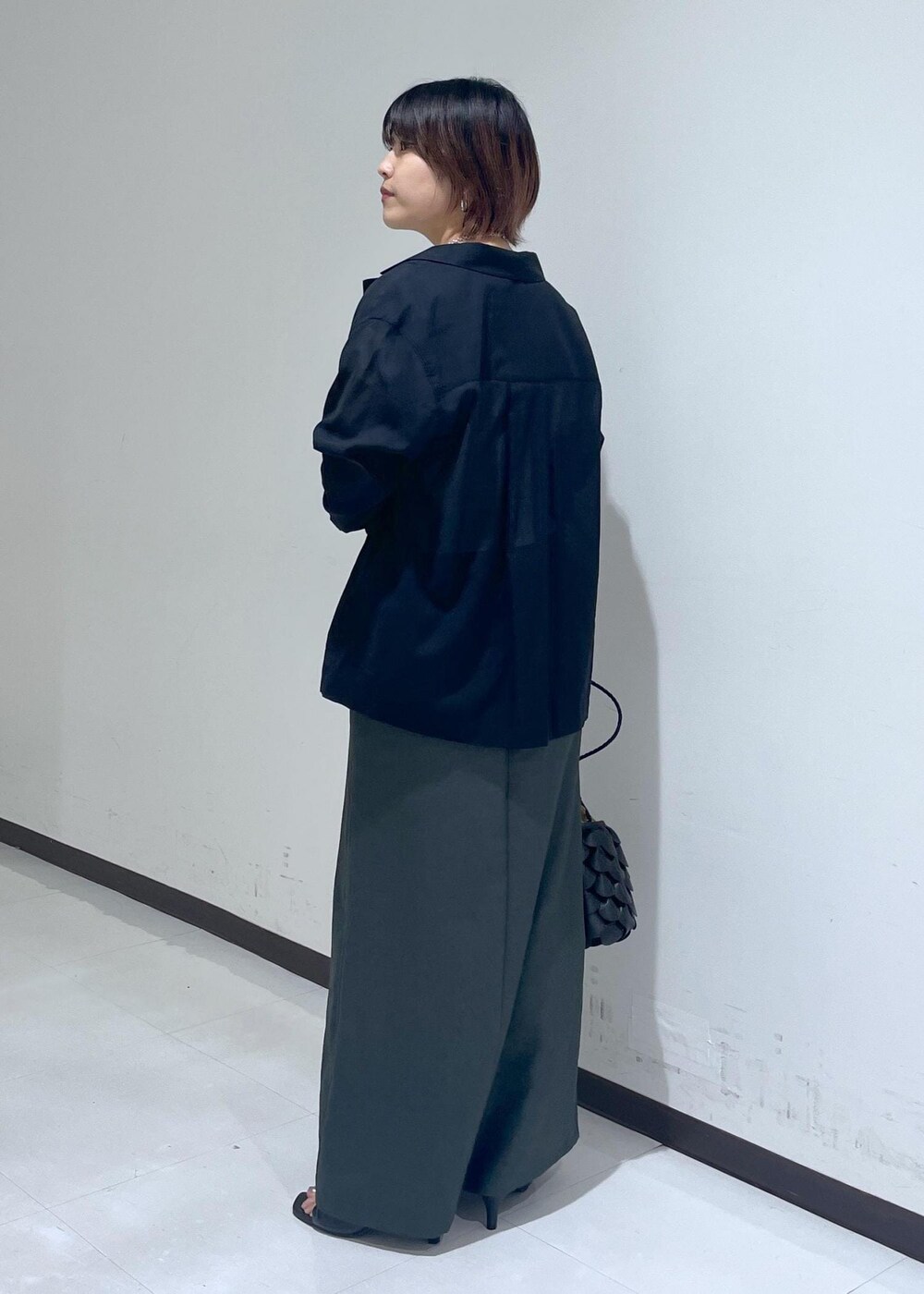 グレー系のスカート、ブラック系のテーラードジャケット、ホワイト系のTシャツ/カットソーを着用したレディースの夏コーディネートの2枚目の写真