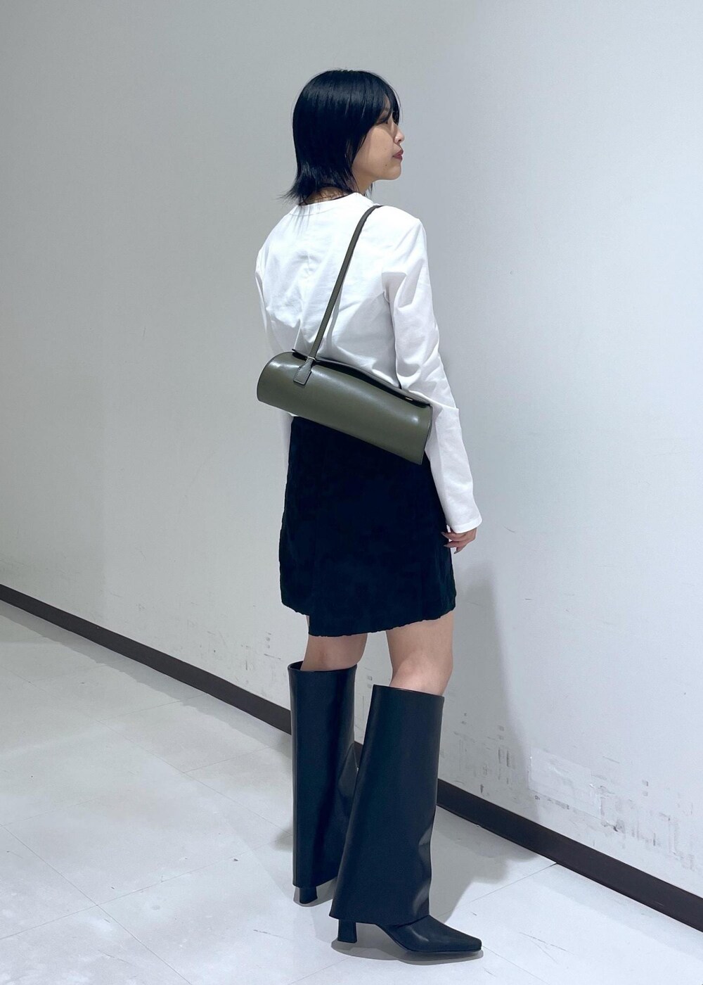 ブラック系のスカート、ブラック系のブーツ、ホワイト系のTシャツ/カットソーを着用したレディースの秋コーディネートの6枚目の写真