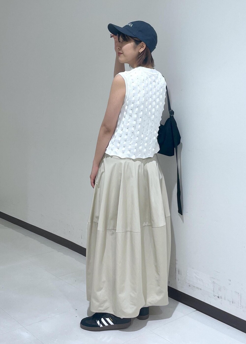 ベージュ系のスカート、ホワイト系のニット/セーター、ブルー系のキャップを着用したレディースの夏コーディネートの3枚目の写真