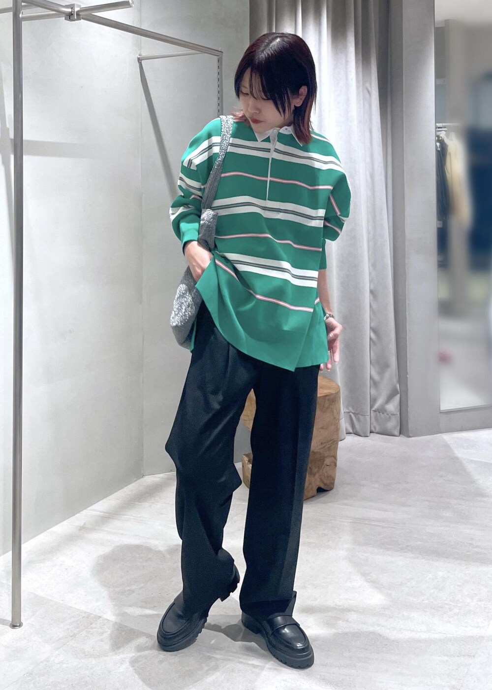 グリーン系のニット/セーター、ブラック系のスラックス、シルバー系のトートバッグを着用したレディースの冬コーディネートの2枚目の写真