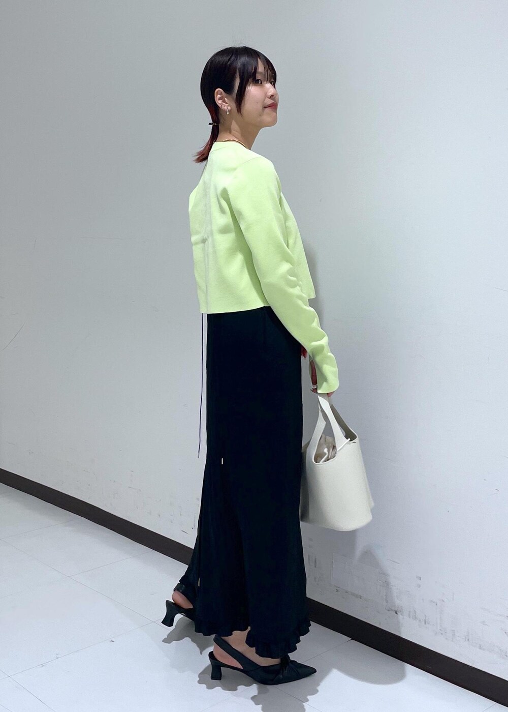 ブラック系のパンプス、ブラック系のワンピース、グリーン系のカーディガン/ボレロを着用したレディースの春コーディネートの4枚目の写真