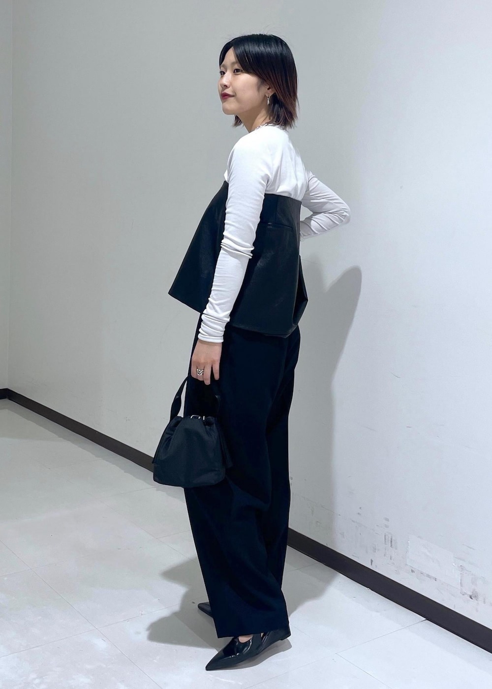 ブラック系のハンドバッグ、グレー系のTシャツ/カットソー、ブラック系のパンプスを着用したレディースの夏コーディネートの3枚目の写真