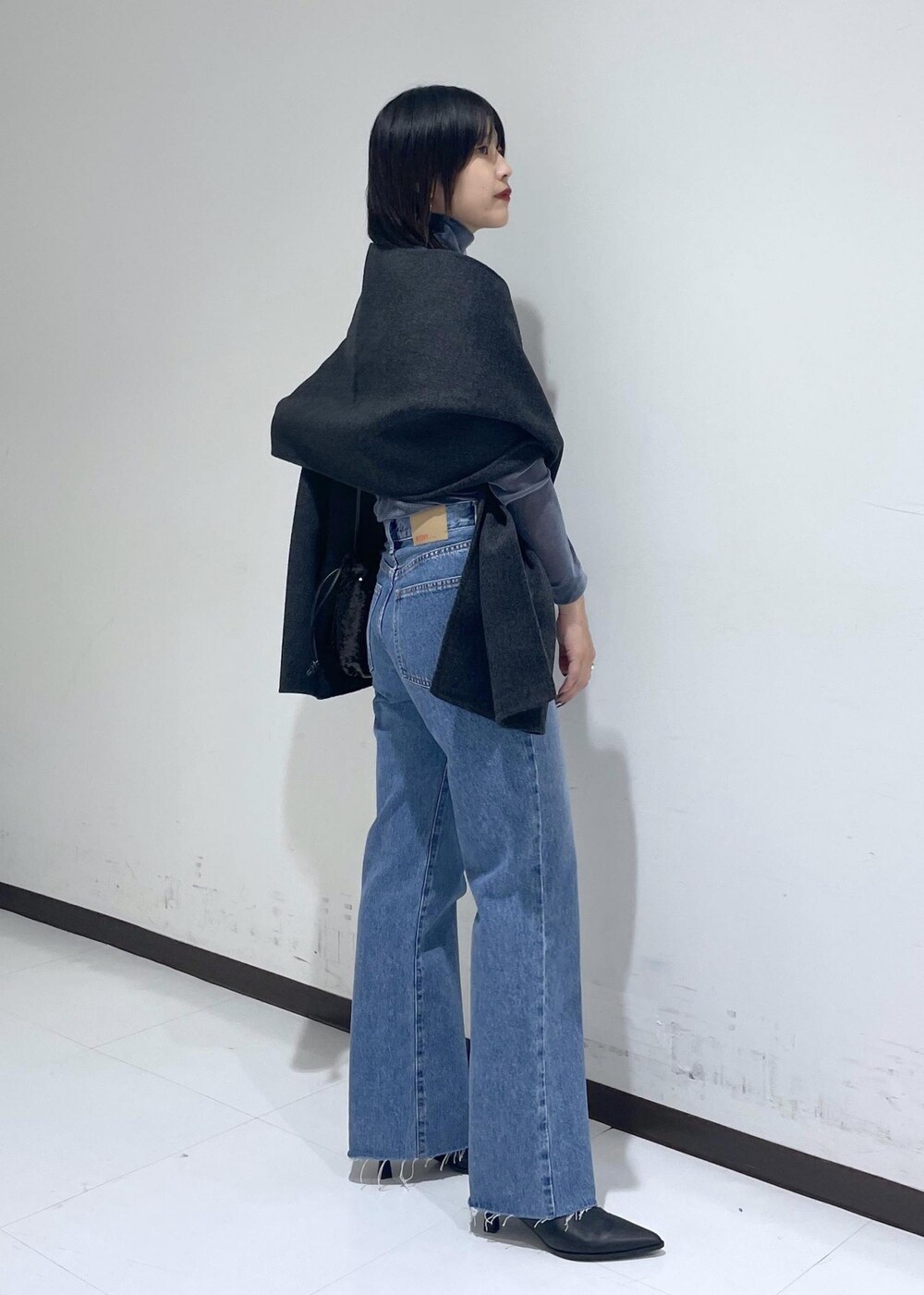 ブラック系のブーツ、ブルー系のデニムパンツ、ブラック系のハンドバッグを着用したレディースの秋コーディネートの4枚目の写真