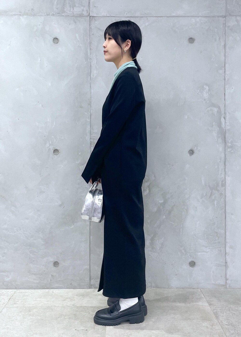 ブラック系のローファー、グリーン系のニット/セーター、シルバー系のショルダーバッグを着用したレディースの冬コーディネートの4枚目の写真