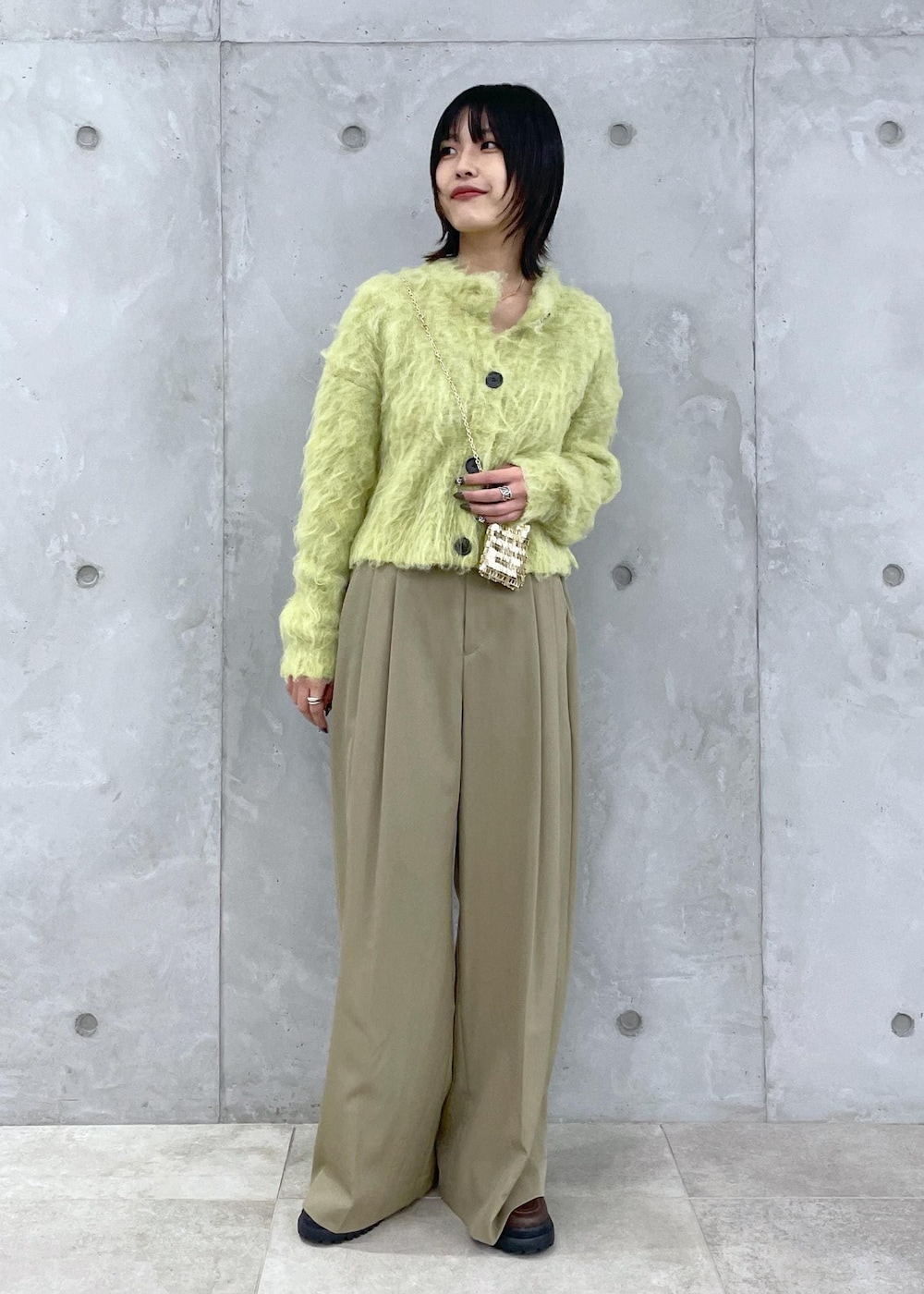 グリーン系のカーディガン/ボレロ、グリーン系のスラックス、ブラウン系のローファーを着用したレディースの秋コーディネートの2枚目の写真