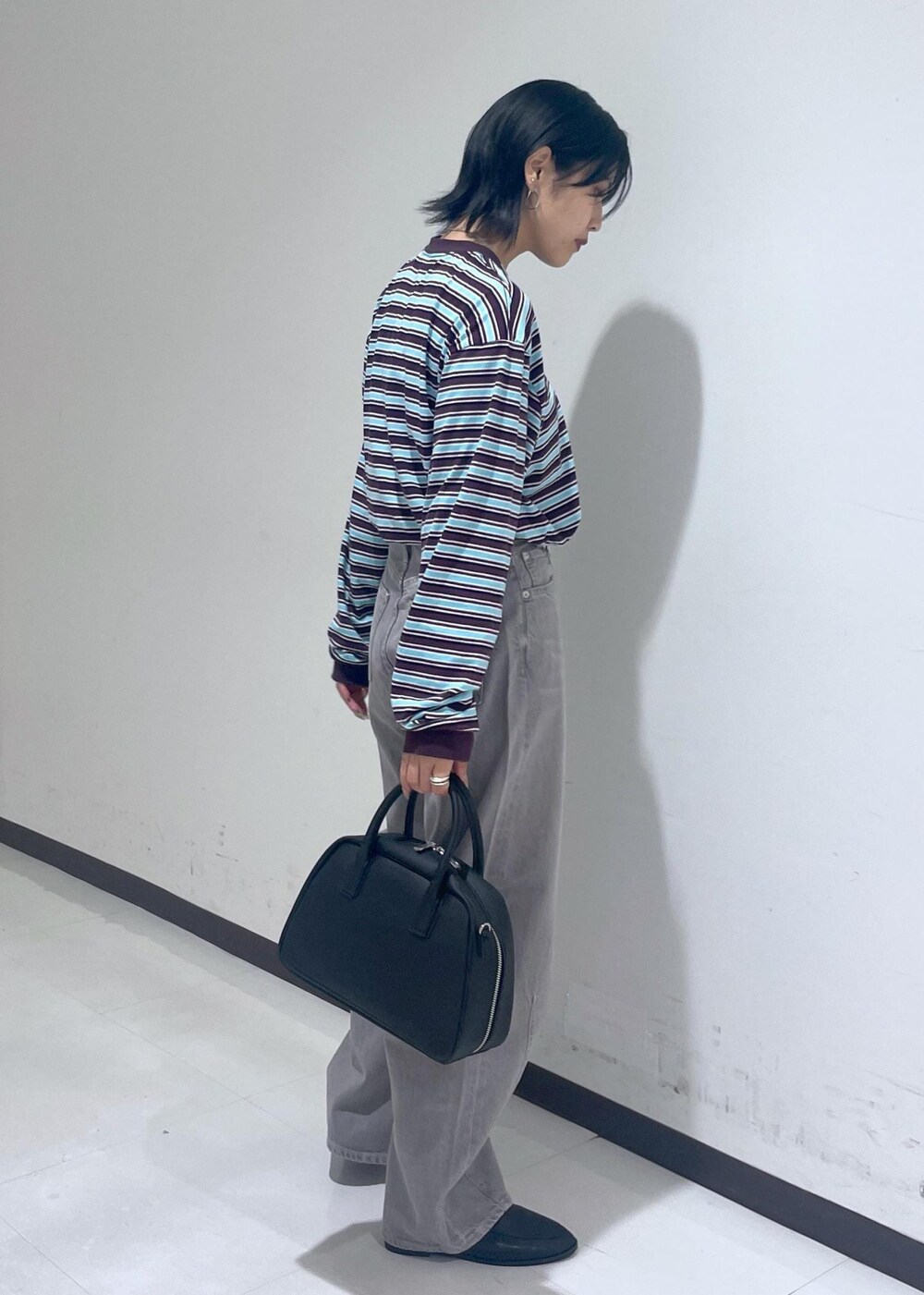 ブラック系のローファー、ブラック系のボストンバッグ、ベージュ系のデニムパンツを着用したレディースの秋コーディネートの7枚目の写真